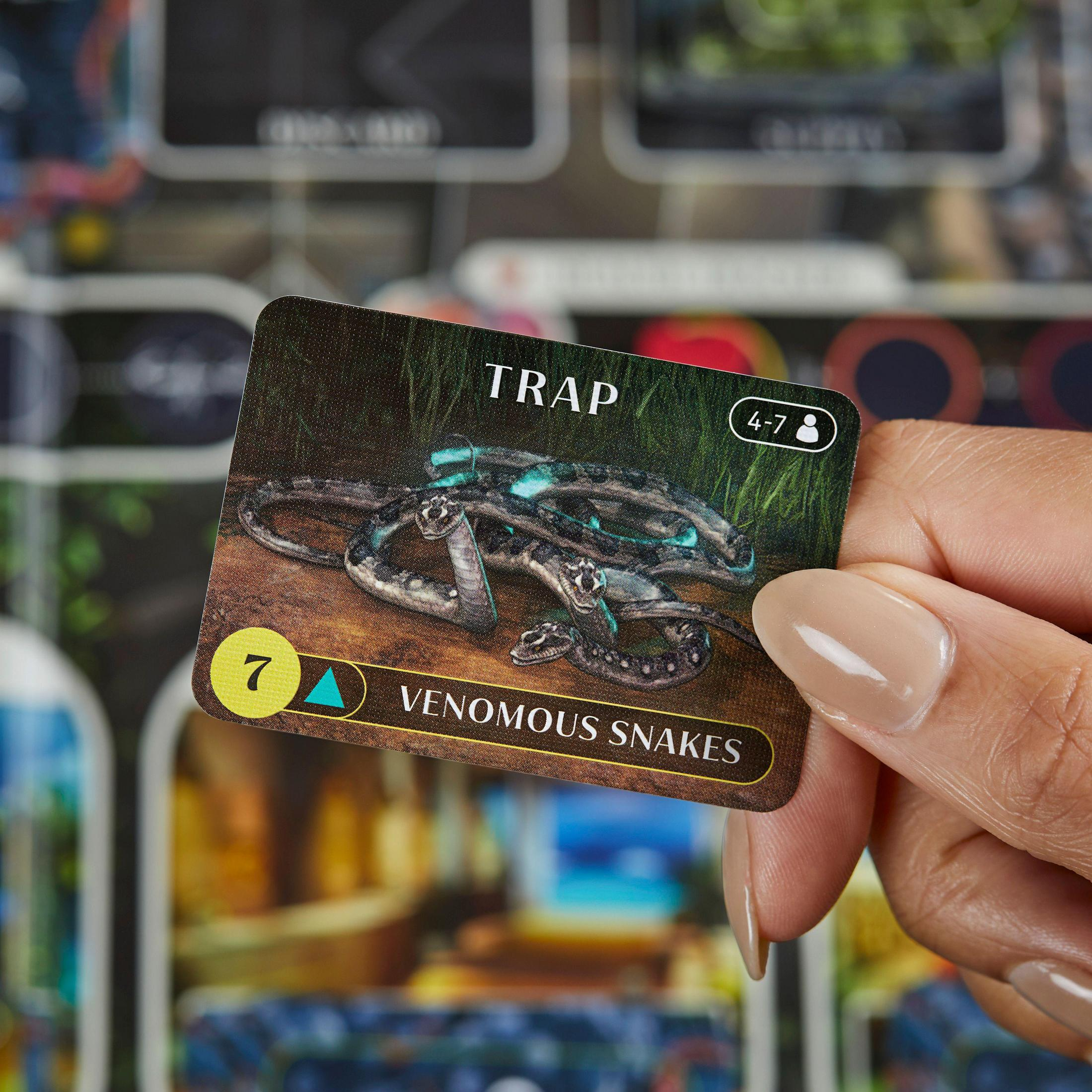 Hand, die eine Spielkarte mit einem Bild von giftigen Schlangen und dem Wort 'TRAP' hält.