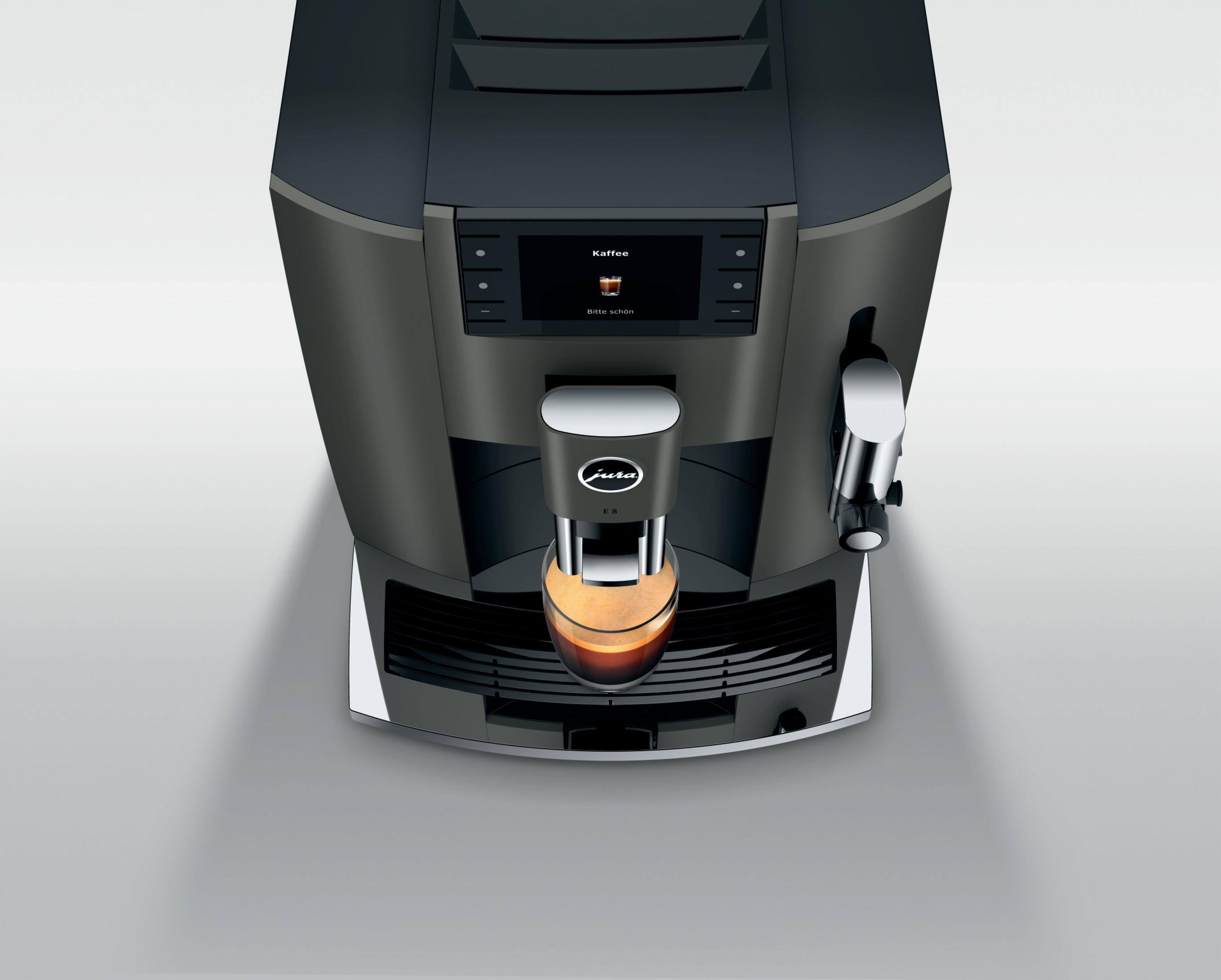 Kaffeemaschine. Schwarz und grau mit Bildschirm. Kaffee fließt in ein Glas. Weißer Hintergrund.