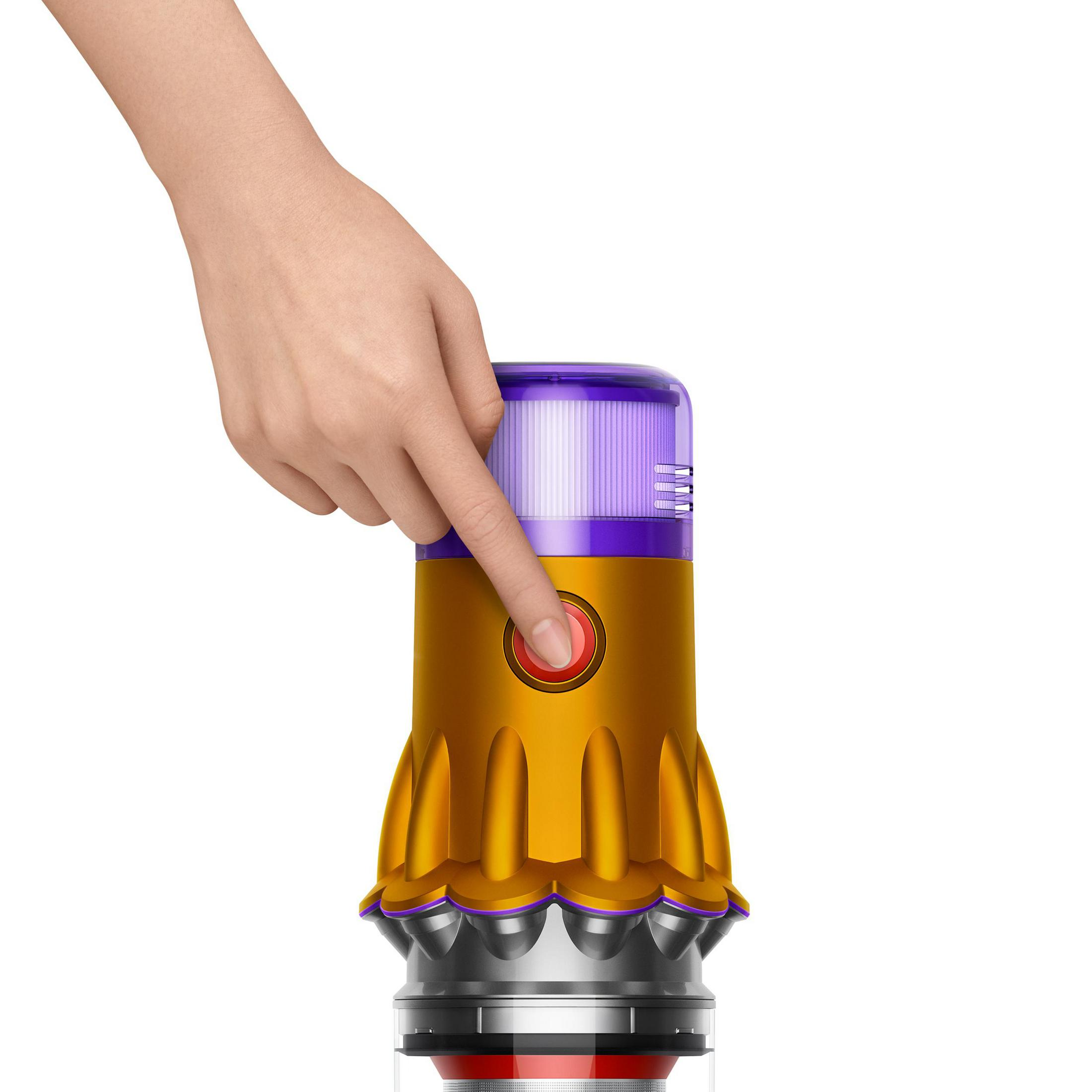 Una mano preme un pulsante rosso su un aspirapolvere giallo e viola. L'aspirapolvere è in posizione verticale.