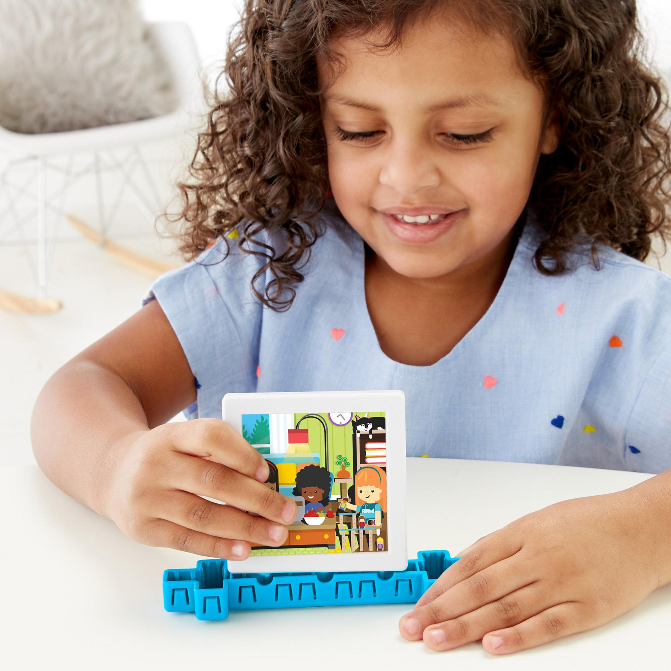 Mädchen spielt mit Spielzeug. Sie betrachtet ein Bild. Das Spielzeug hat Bilder.