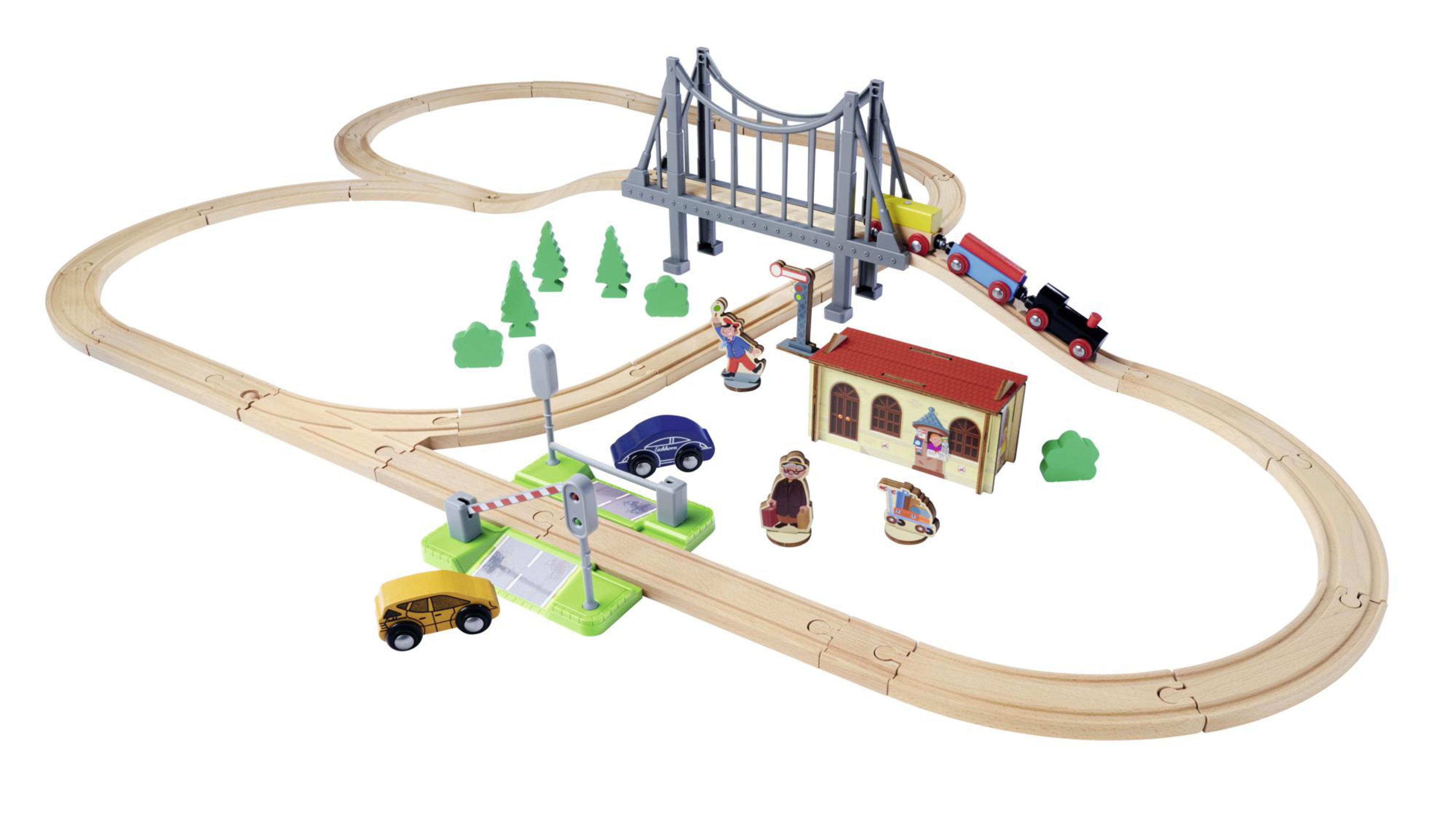 Holzeisenbahn-Set. Es hat eine Brücke, einen Bahnhof und verschiedene Figuren. Der Zug fährt auf einer Holzstrecke.