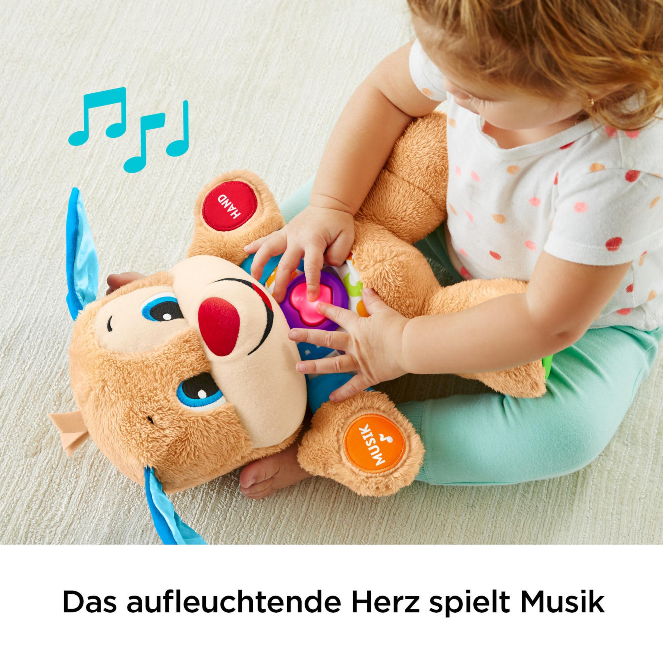 Ein Kleinkind spielt mit einem Plüschhund-Spielzeug mit Noten.