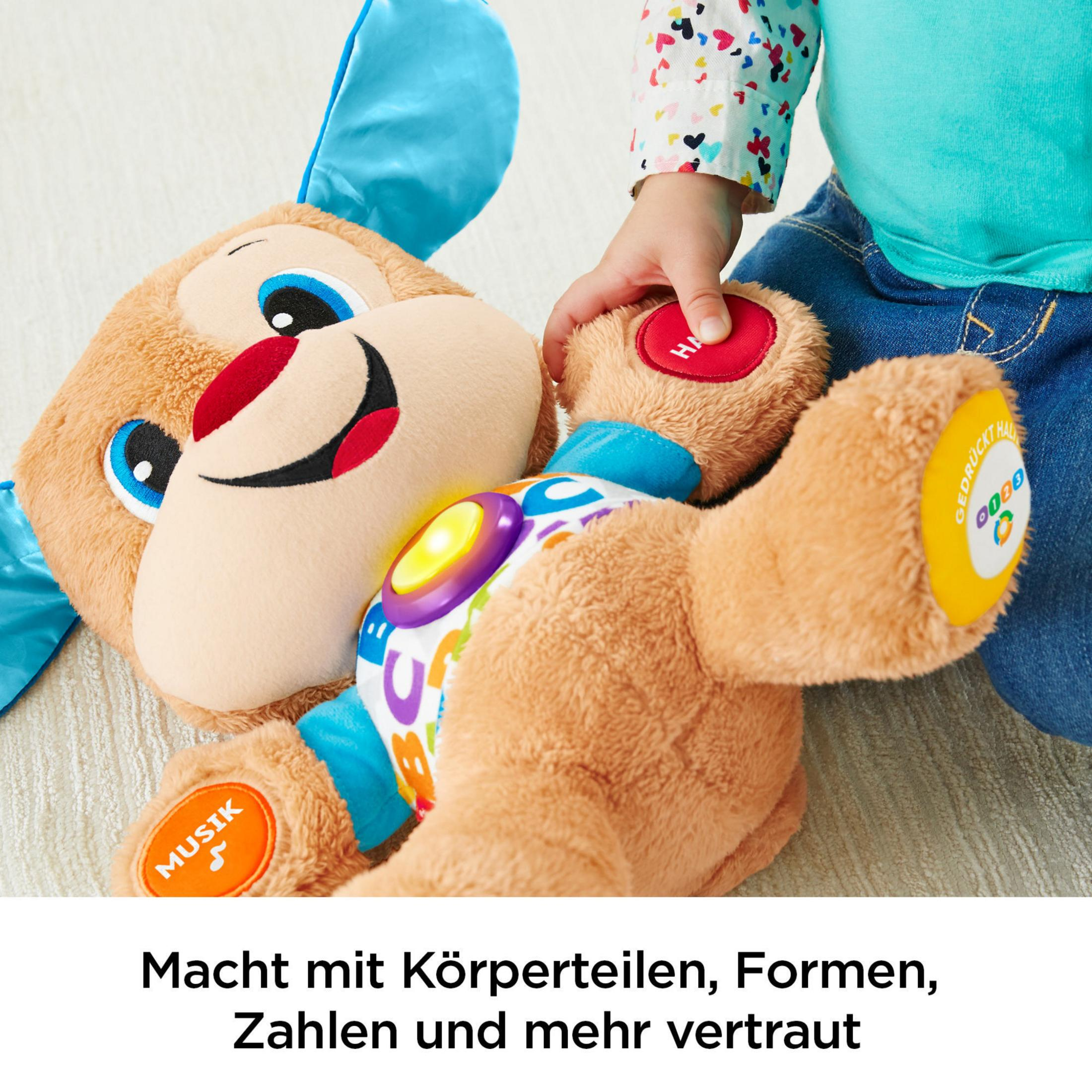 Ein Spielzeughund mit Kinderhand darauf. Das Spielzeug hat einen roten Knopf und eine Musiknote.