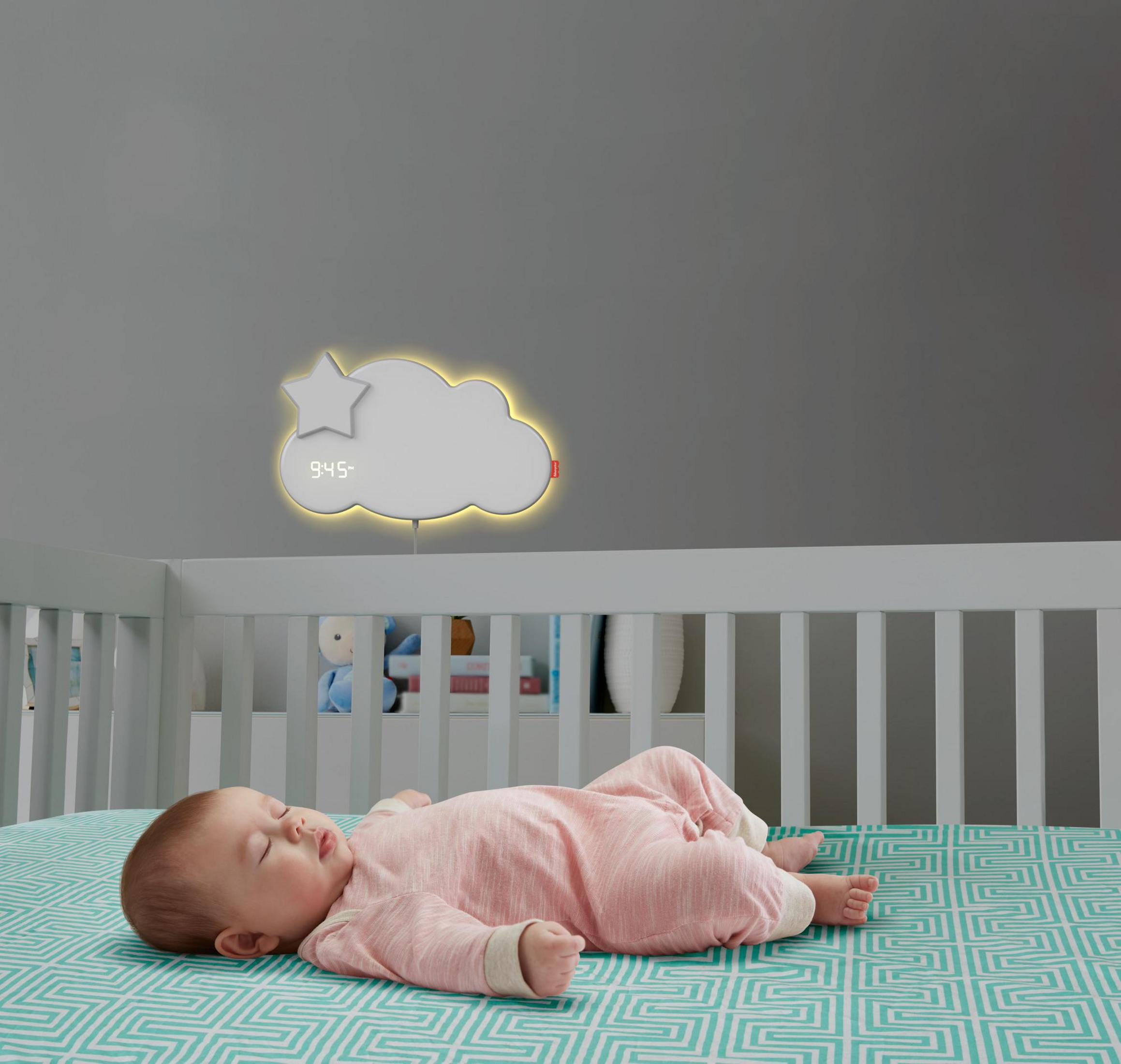 Baby schläft in einem Kinderbett, mit einem wolkenförmigen Nachtlicht und einem Stern.