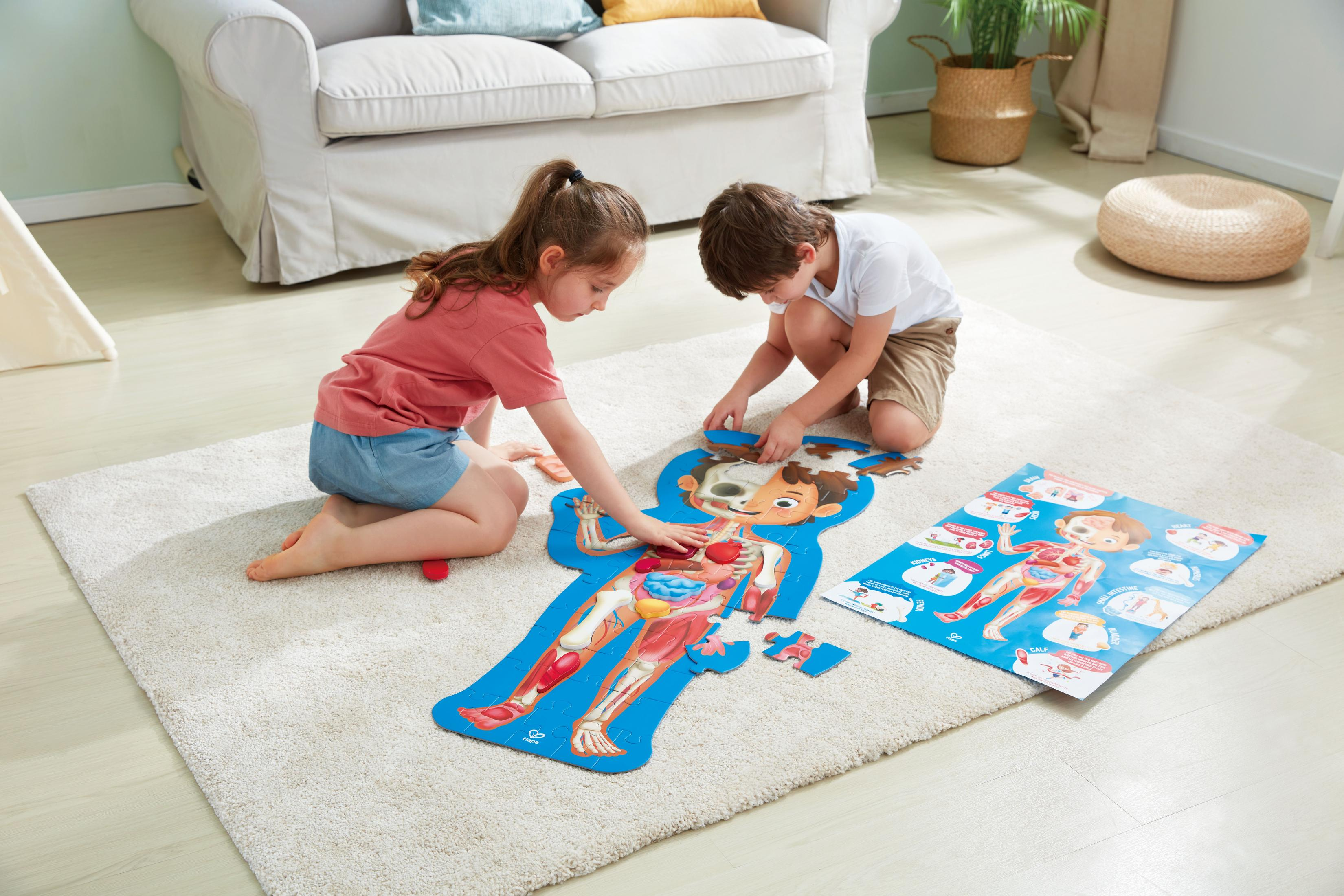 Bambini che assemblano un puzzle del corpo umano su un tappeto.