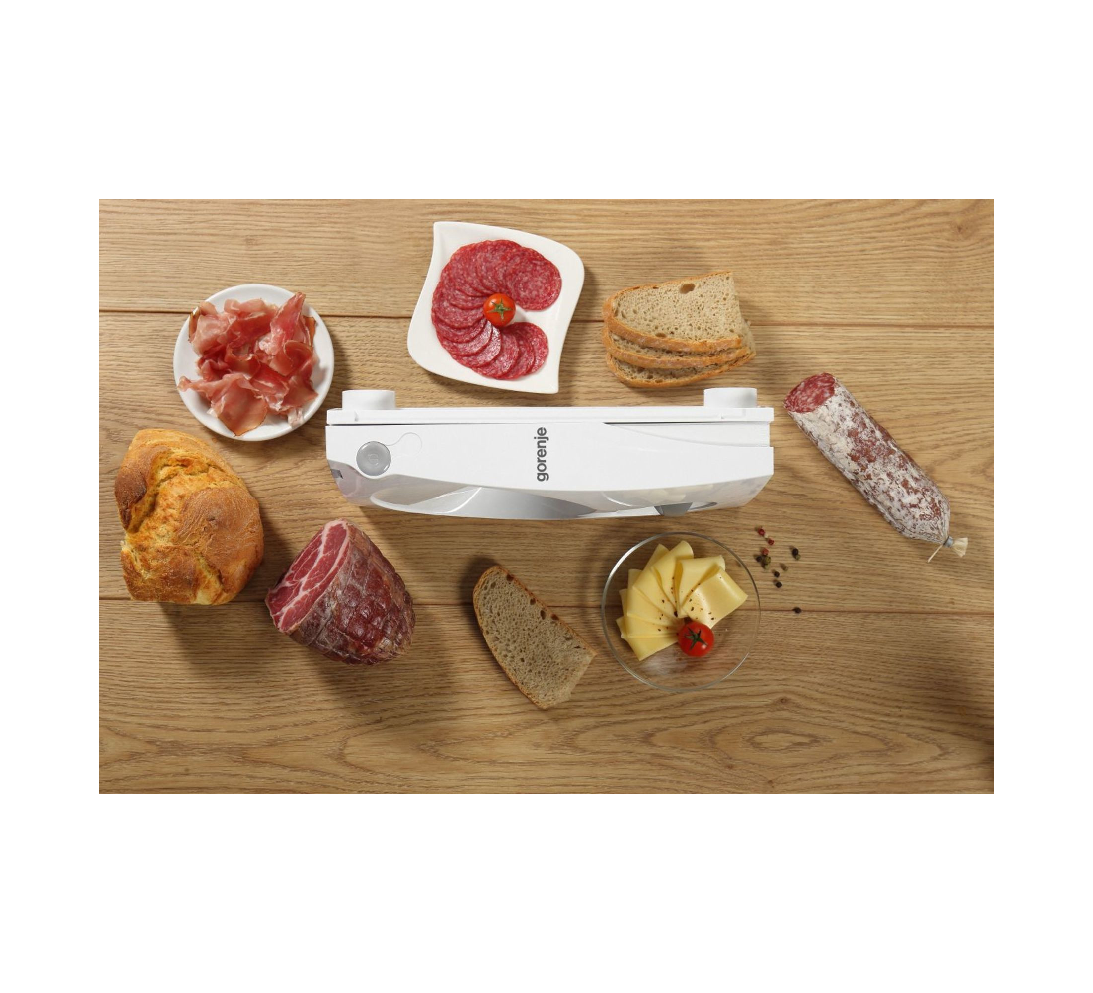 Jedzenie na drewnianym stole: salami, ser, chleb i zgrzewarka próżniowa.