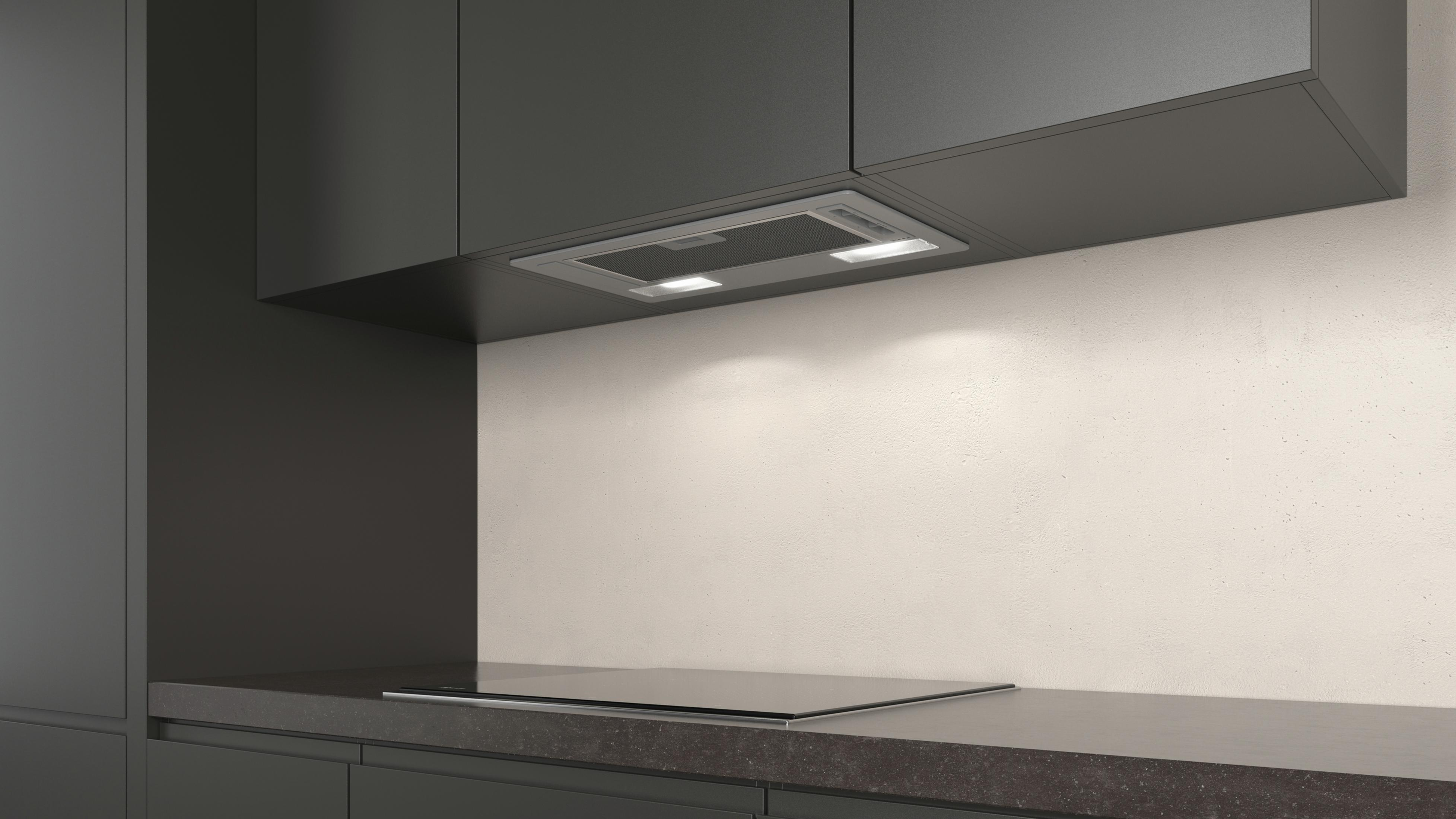 Cocina con gabinetes negros, una campana extractora de acero inoxidable y una placa de inducción.