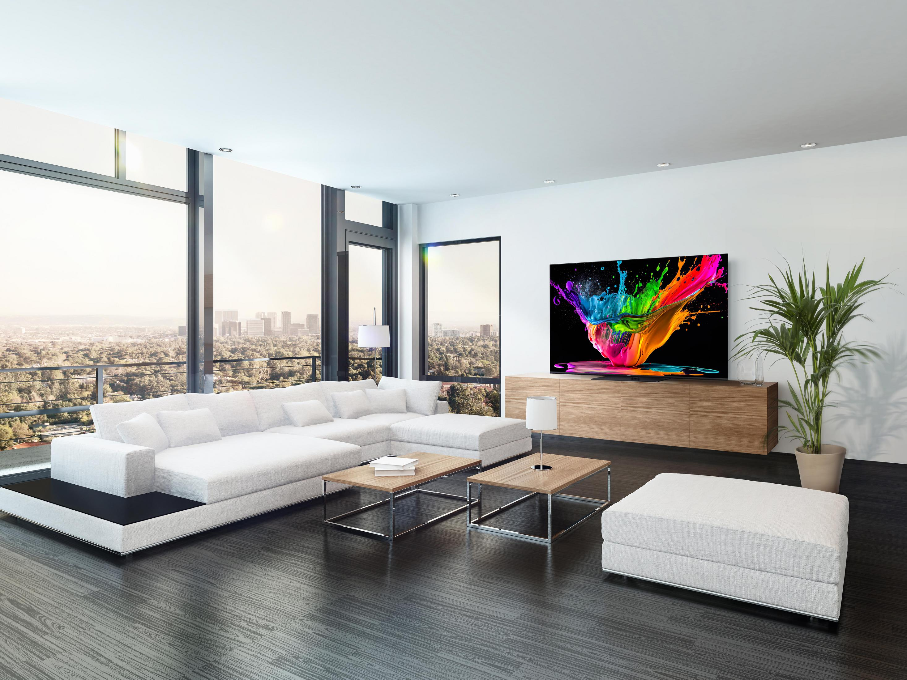 Soggiorno moderno con divano bianco, pavimento nero e arte a spruzzo colorata.