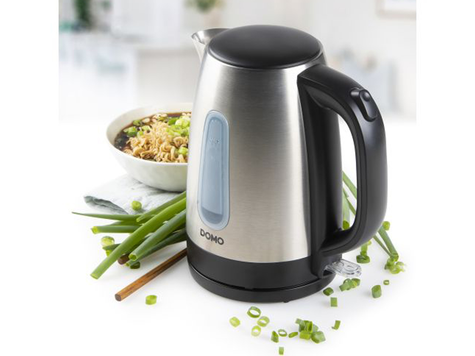 Czajnik elektryczny ze stali nierdzewnej z czarnym uchwytem, szczypiorkiem i makaronem.