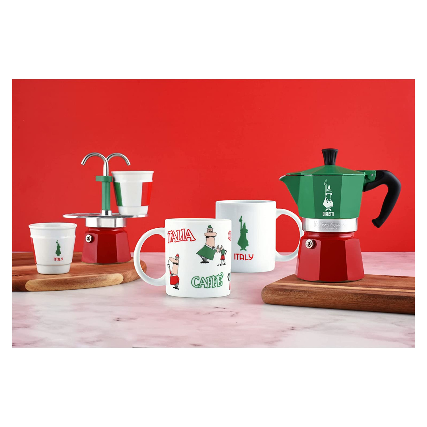 Martwa natura z włoskim ekspresem do kawy i filiżankami. Czerwone tło, drewniane deski.