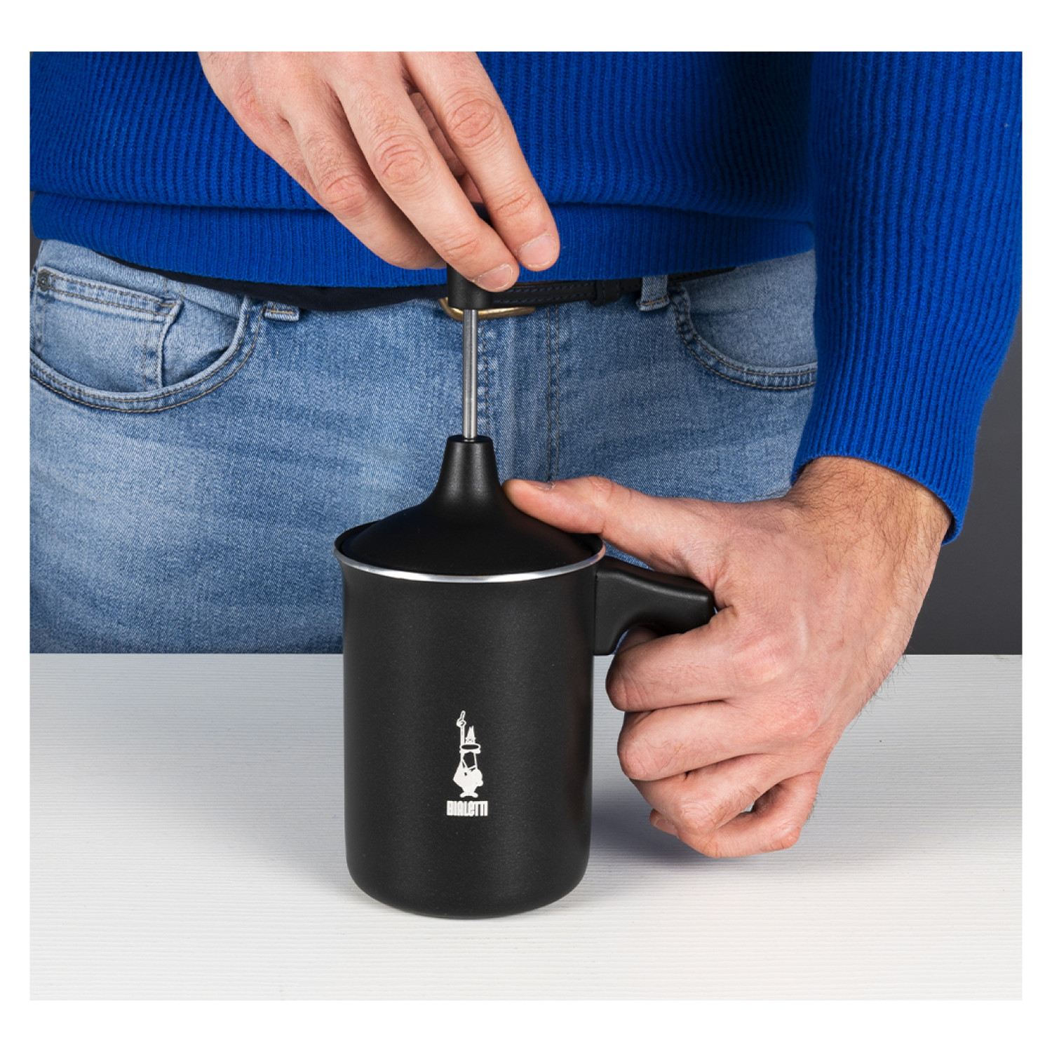 Osoba używająca czarnego spieniacza do mleka. Widoczne logo Bialetti.