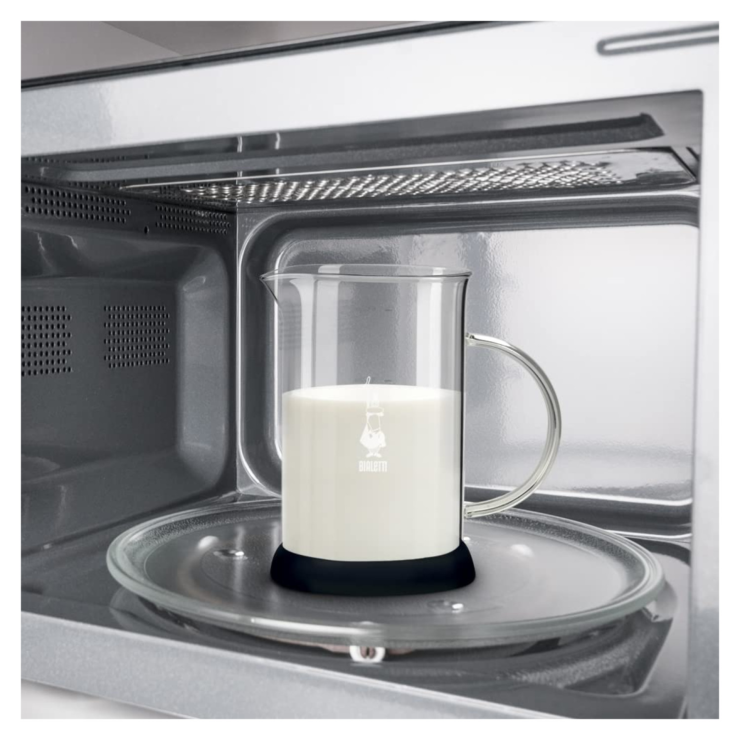 Szklana karafka z mlekiem wewnątrz kuchenki mikrofalowej.