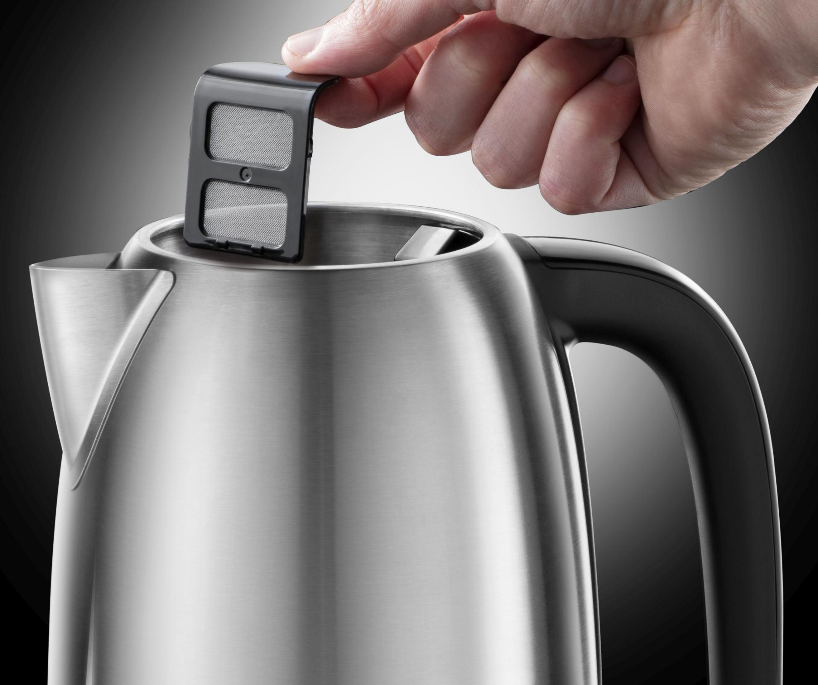A hand removing a filter from a silver kettle. Black and silver kettle, black background.