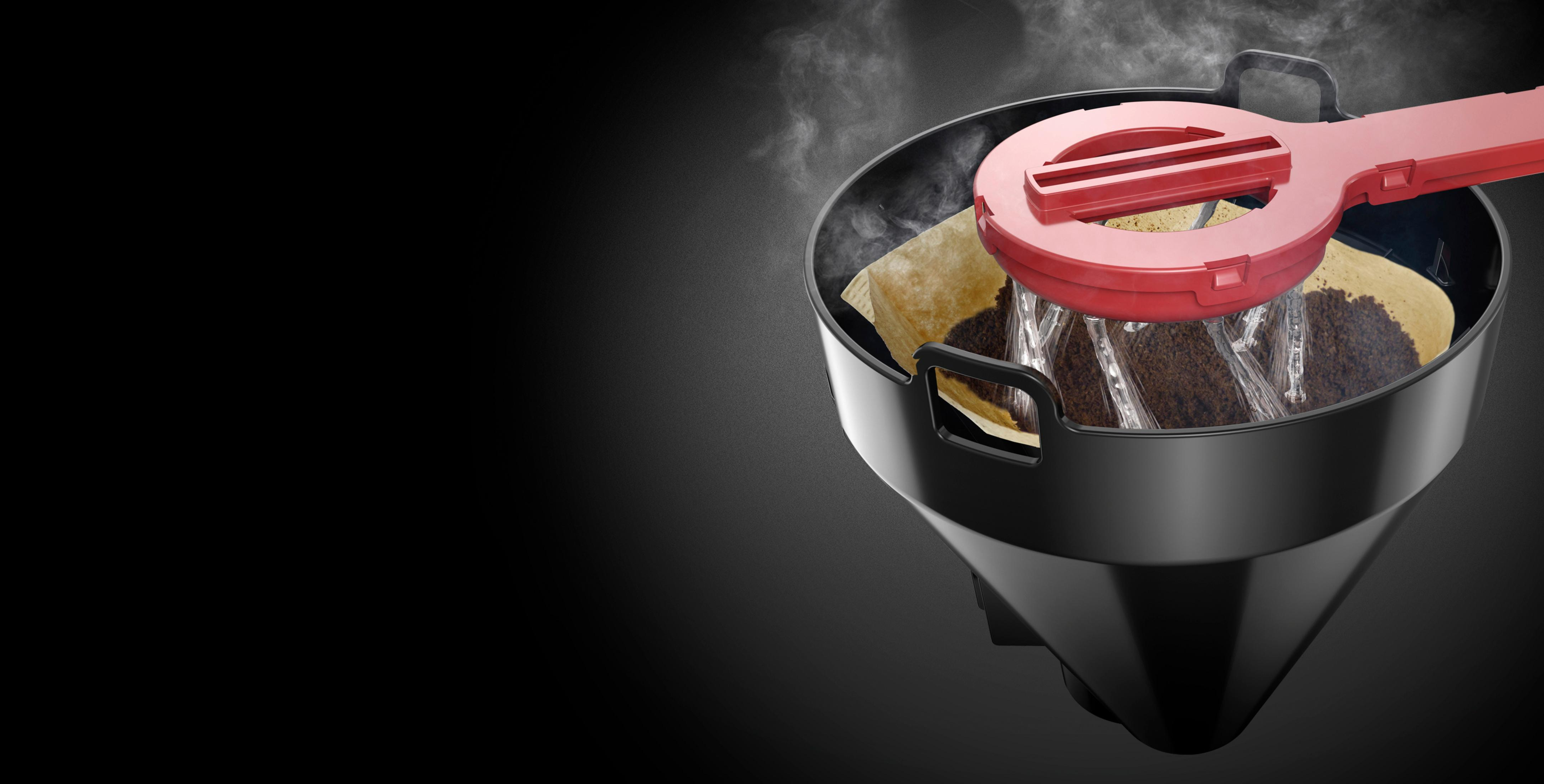 Czarny ekspres do kawy z czerwonym uchwytem parzy kawę, widoczna para.