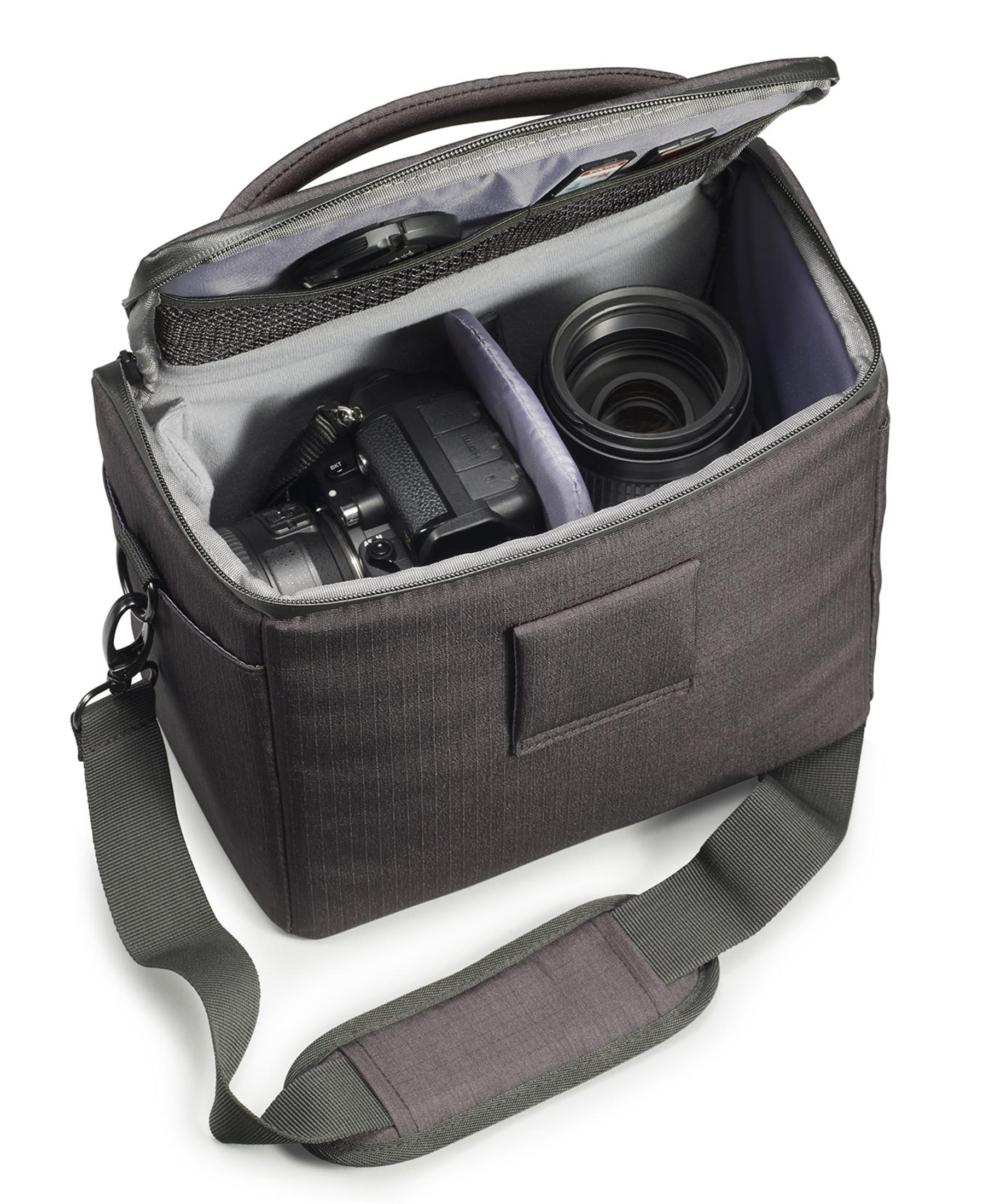 A gray camera bag, open, filled with camera, lens, and accessories. It is on a white background.