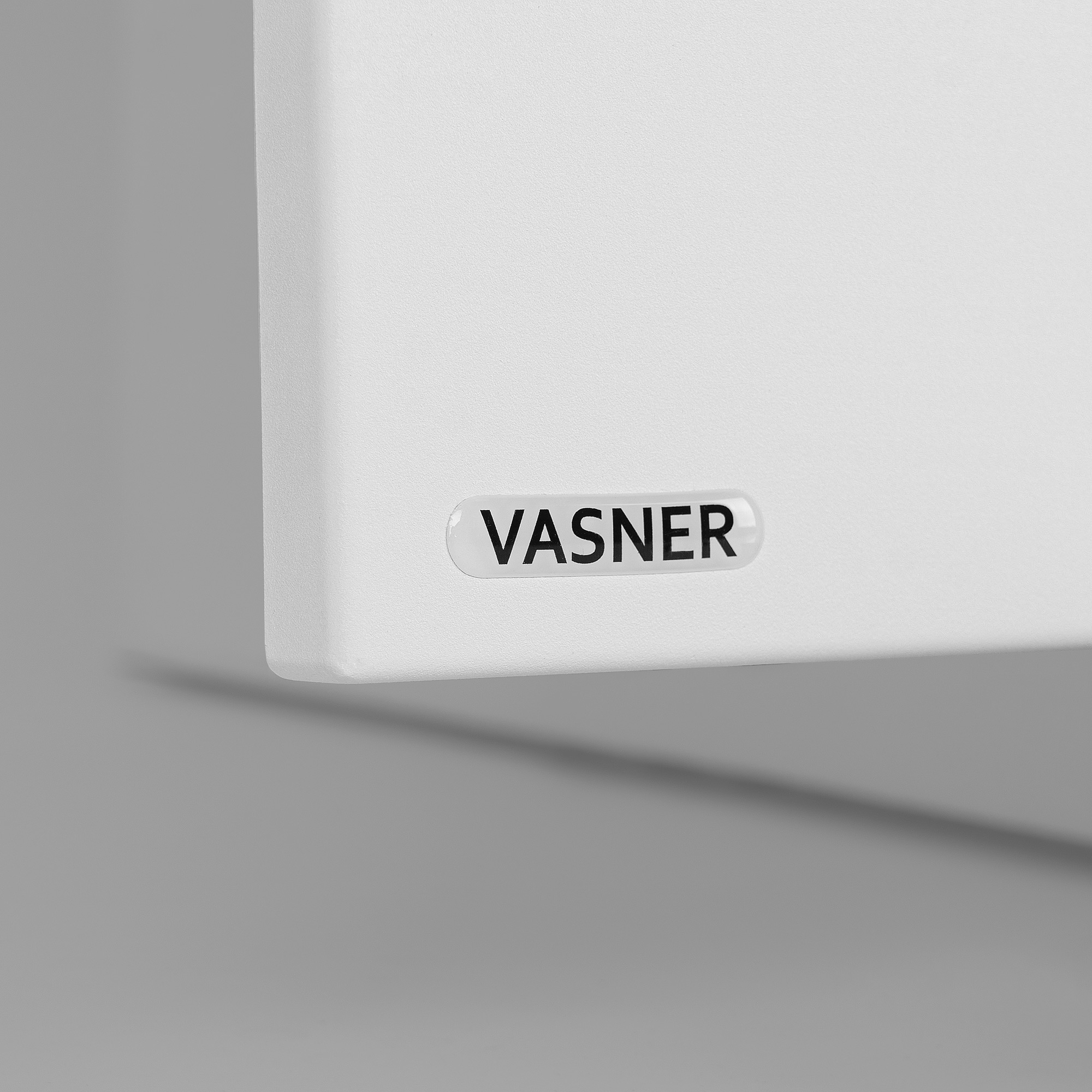 Eine weiße Tafel mit dem Wort 'VASNER' in schwarzen Buchstaben.