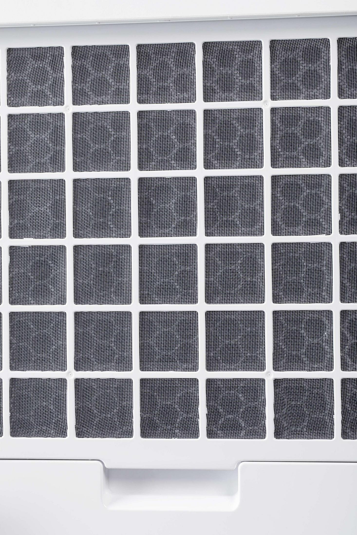 Close-up of a white air filter with a grid of black mesh squares.