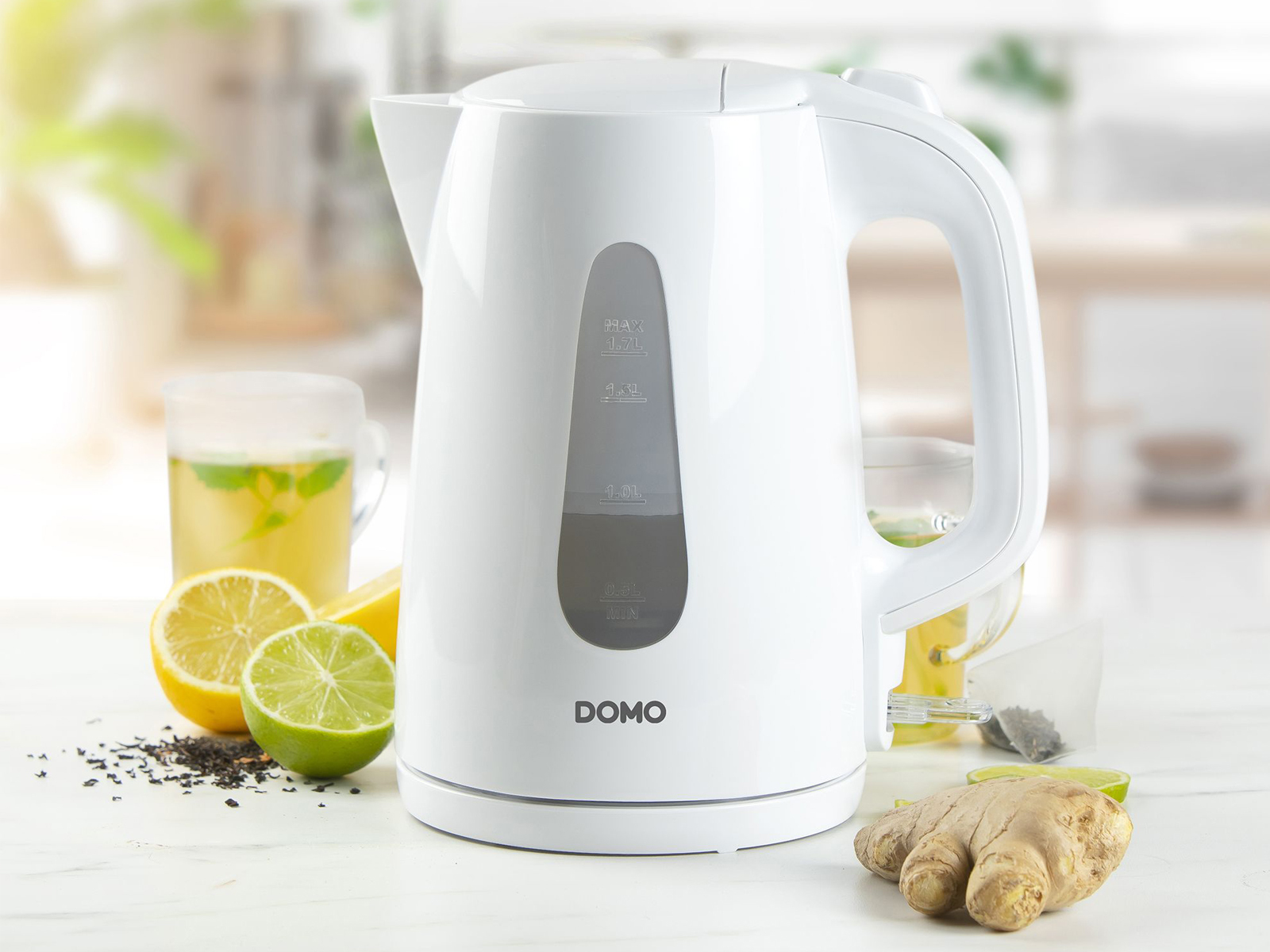 Bollitore elettrico bianco con livello dell'acqua visibile, con limoni, zenzero e tè.