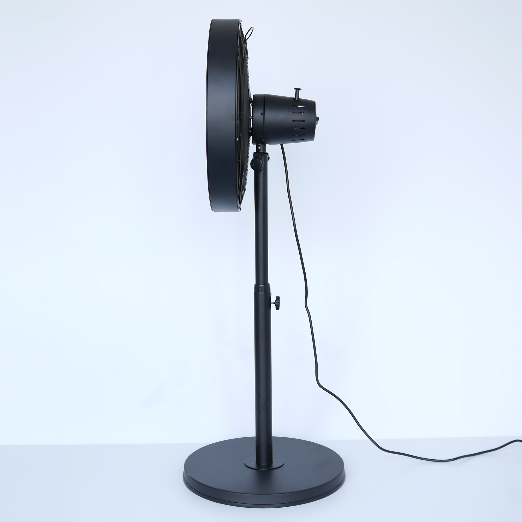 Schwarzer Standventilator mit rundem Fuß, vor weißem Hintergrund, Seitenansicht.
