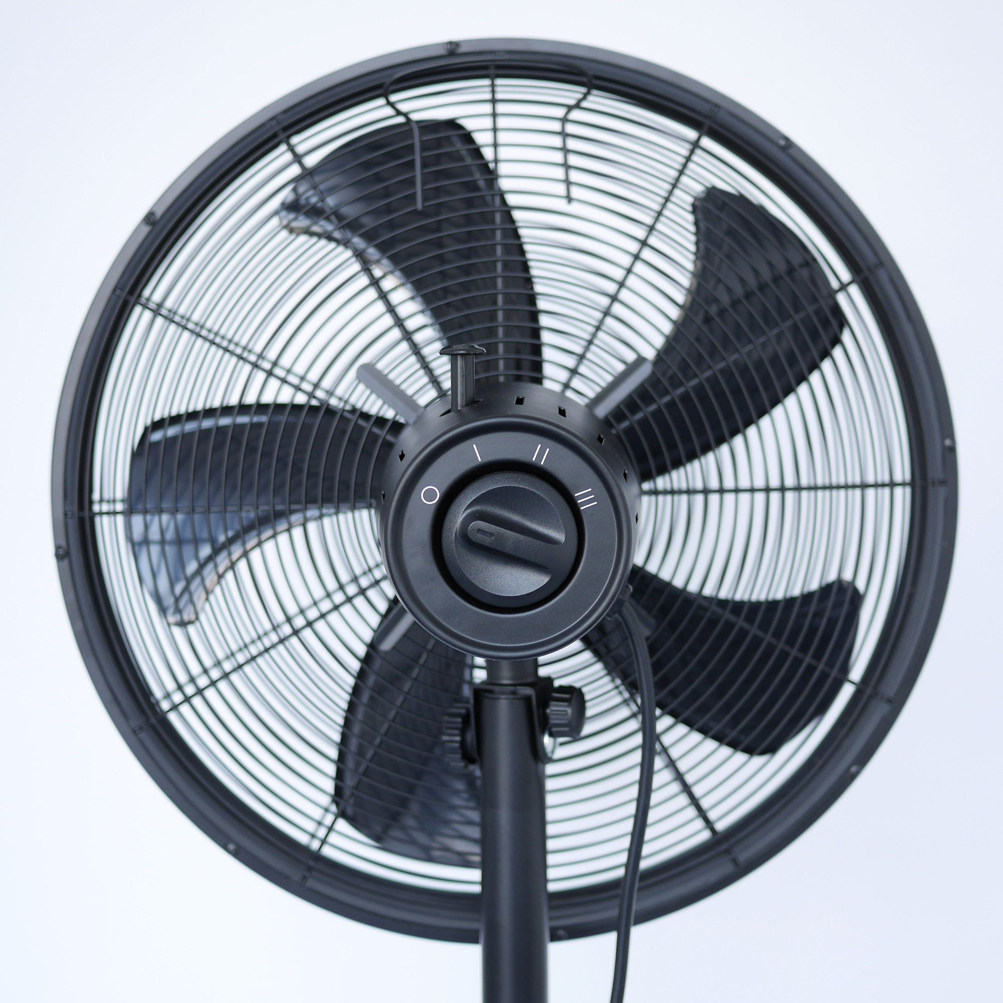 Schwarzer Standventilator mit kreisförmigem Ventilatorkopf. Der Bedienknopf befindet sich in der Mitte.