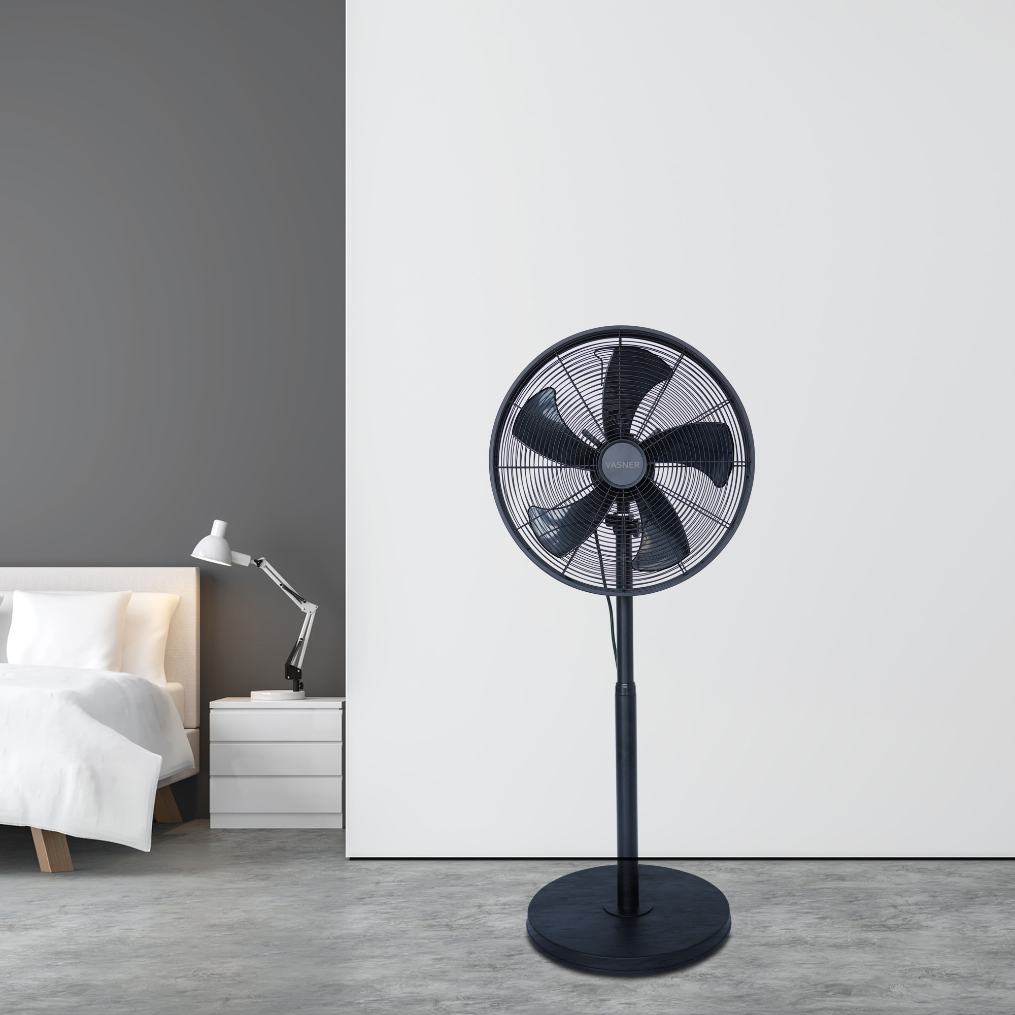 Schwarzer Standventilator in einem Raum, mit Bett und weißer Wand.