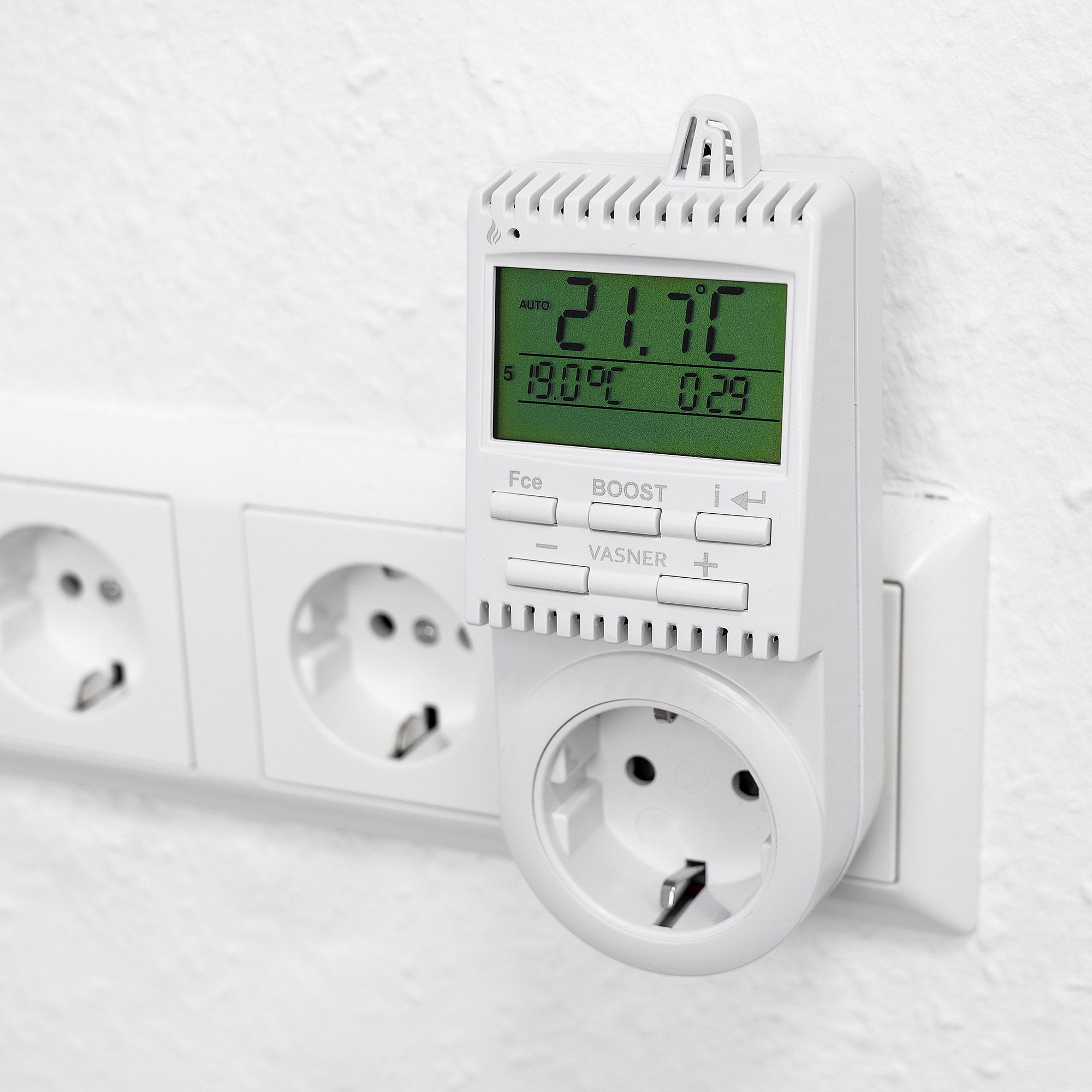 Ein weißer Smart-Thermostat, der in eine Steckdose gesteckt ist und die Temperatur in Celsius anzeigt.
