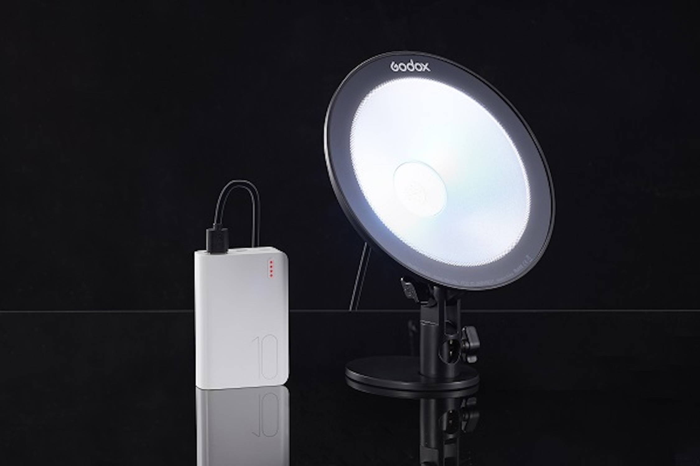 Lumière blanche ronde avec une banque d'alimentation. La lumière est sur un support noir.