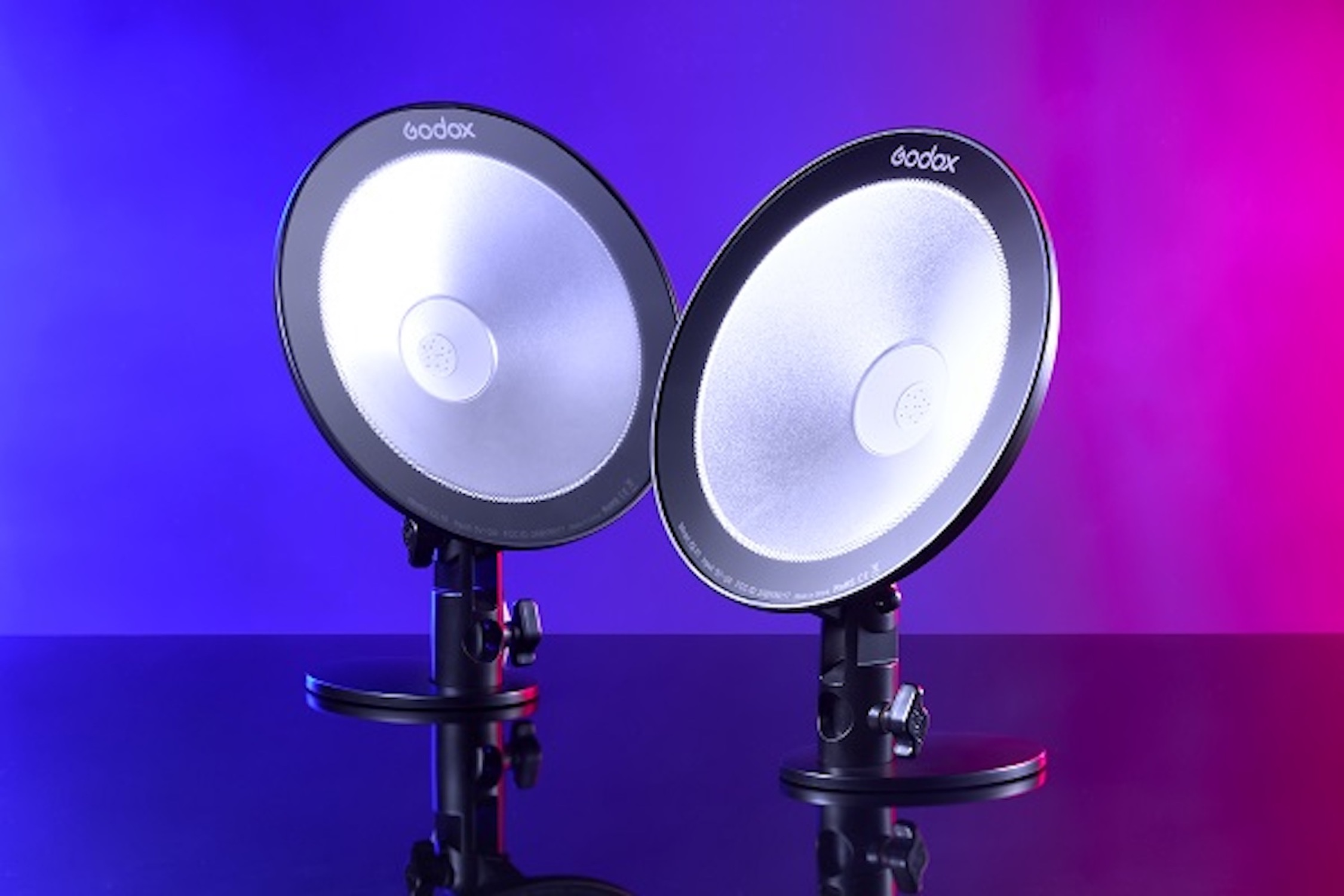 Deux lumières de studio sur un fond dégradé bleu et rose, avec la marque Godox.