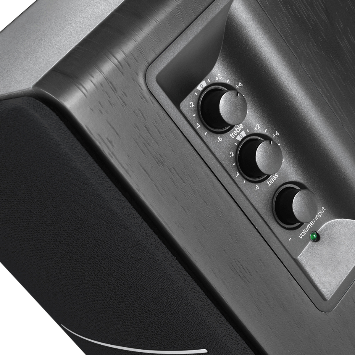 Zbliżenie czarnego głośnika z drewnianym wykończeniem. Posiada pokrętła regulacji tonów wysokich, niskich i głośności.