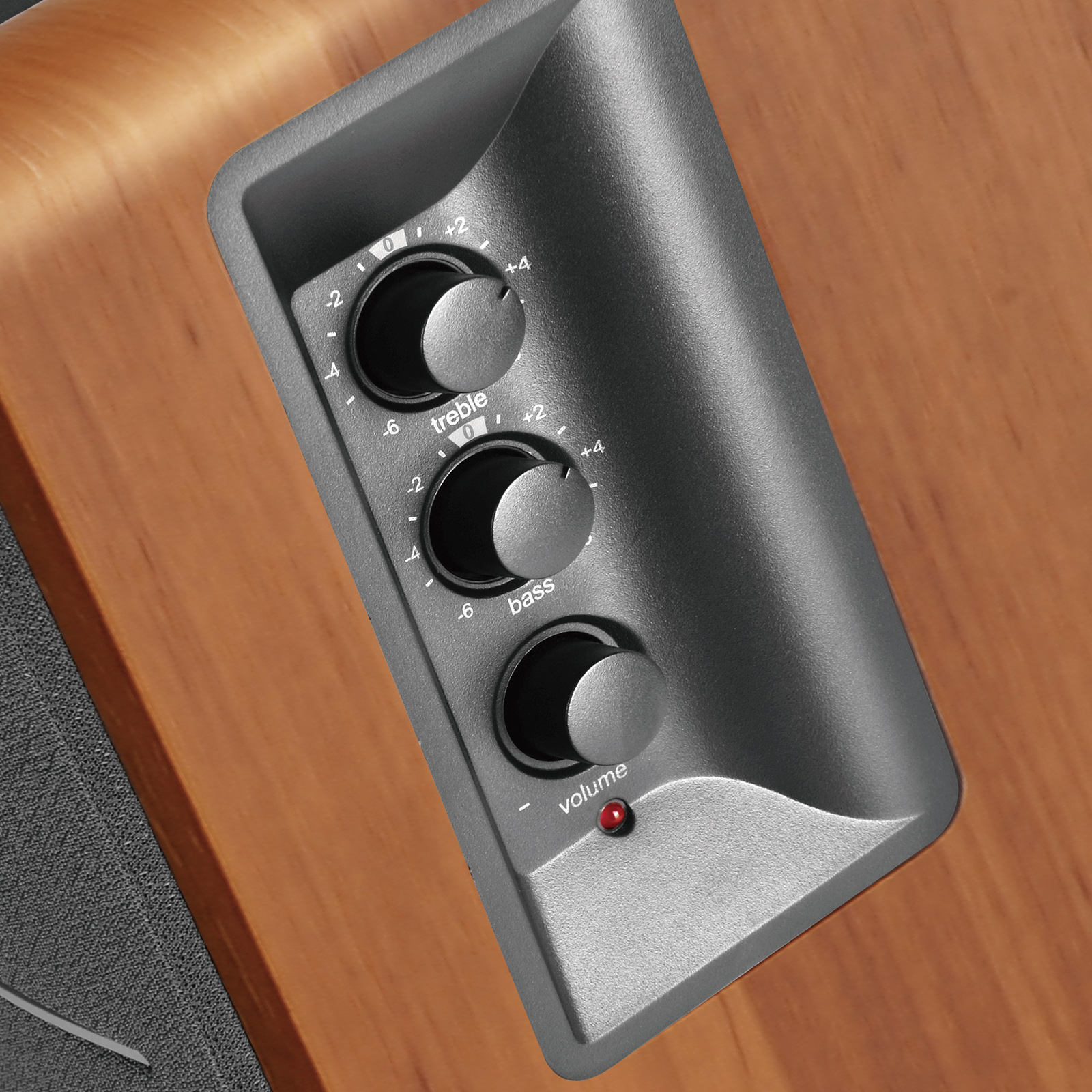 Nahaufnahme von Reglern eines Soundsystems auf Holzoberfläche. Regler für Höhen, Bässe und Lautstärke.