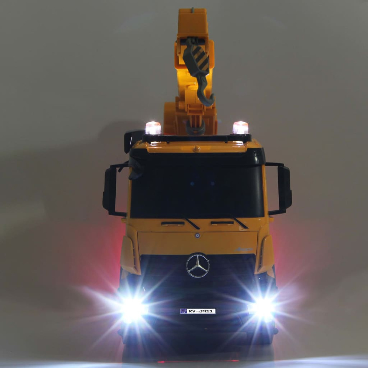 Gelber Spielzeug-Baufahrzeug mit Blinklichtern. Ausleger ist ausgefahren. Lichter sind an. Mercedes-Logo sichtbar.