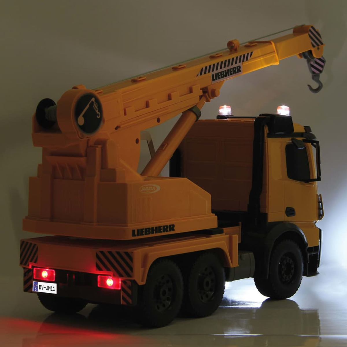 Orangefarbenes Kranwagen-Spielzeug mit Lichtern. Schwarze Räder. Weißer Hintergrund.