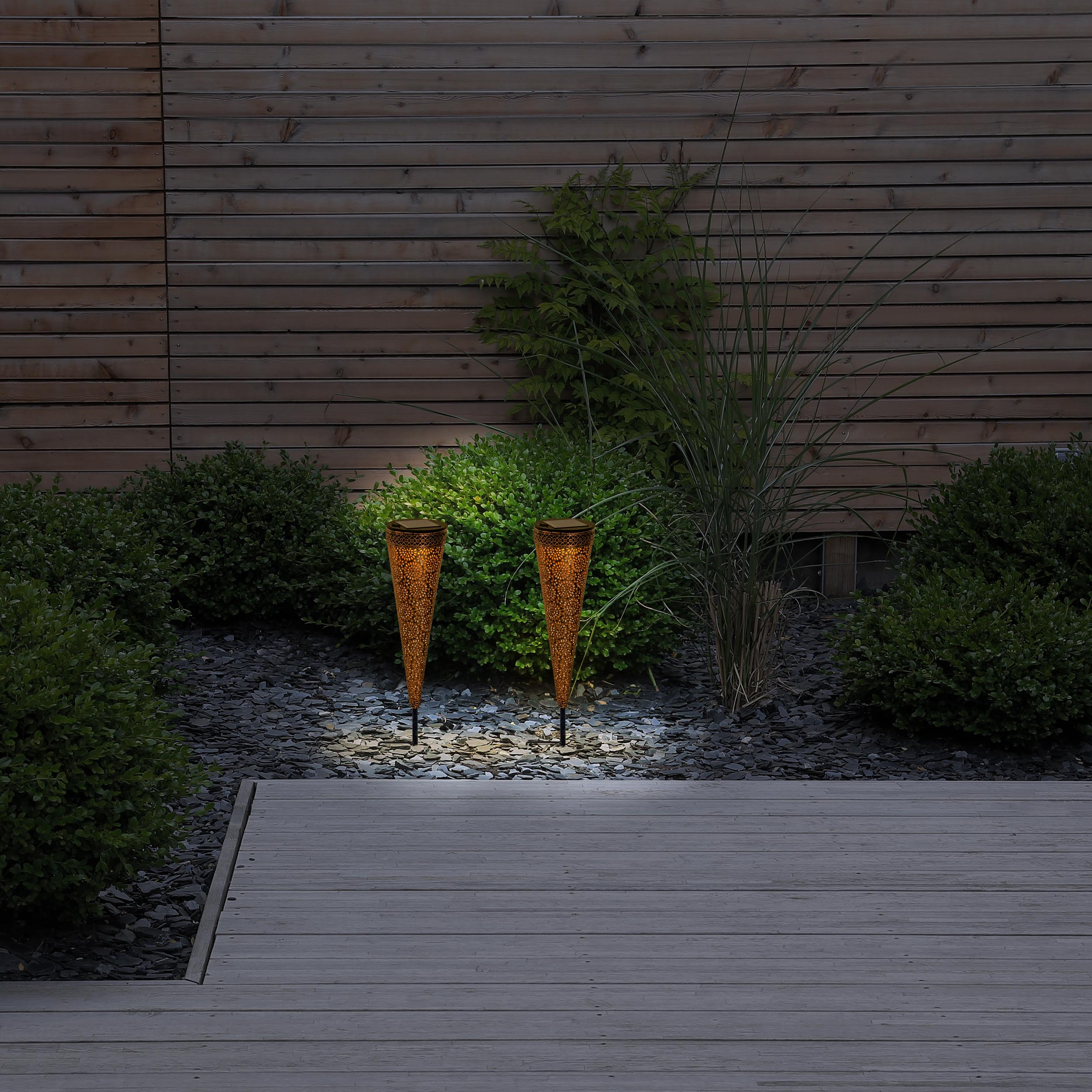 Zwei Outdoor-Lichtfackeln in einem Garten auf einem Holzdeck.