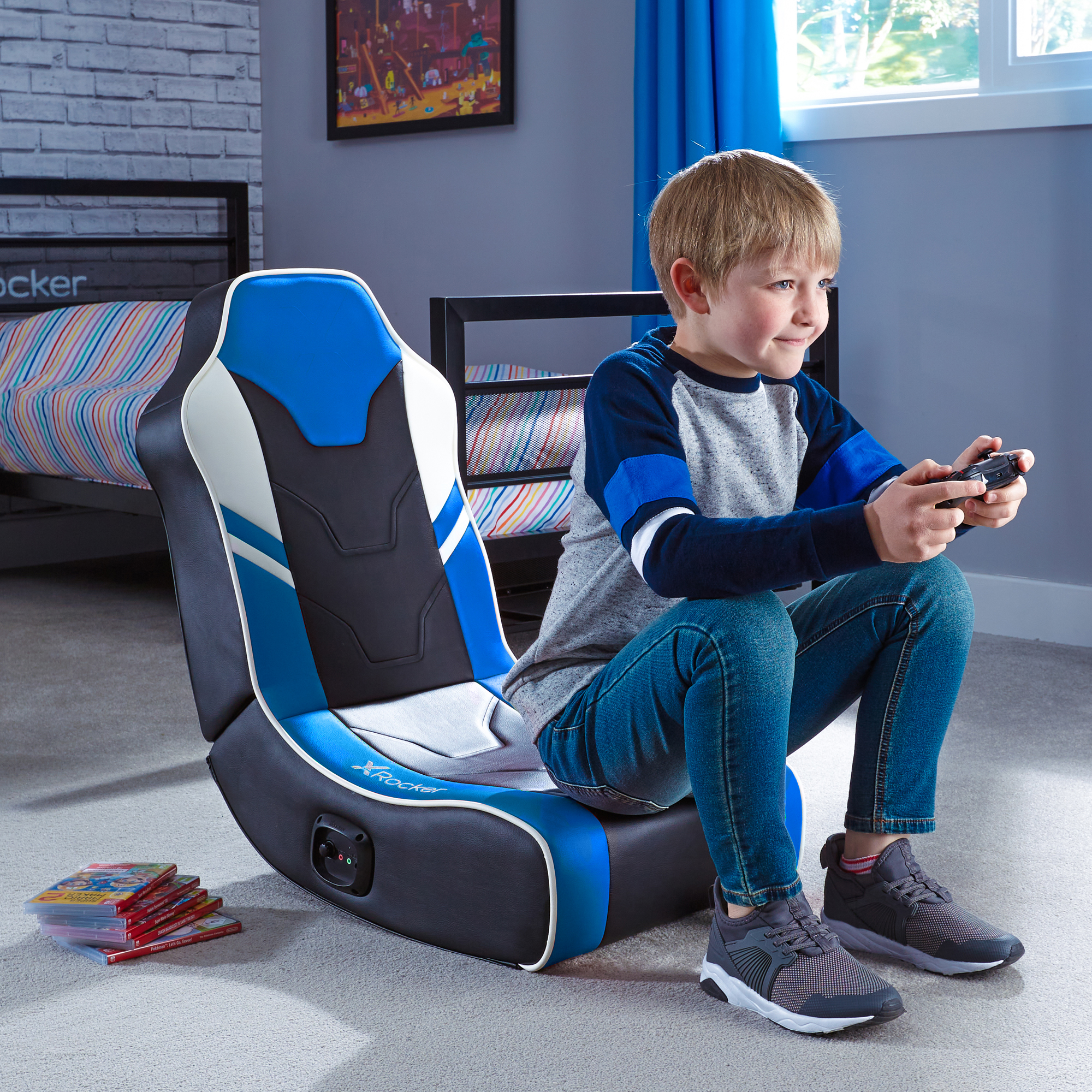 Junge im Gaming-Stuhl mit Controller. Spiele auf dem Boden, Bett im Hintergrund. Zimmer ist grau und blau.