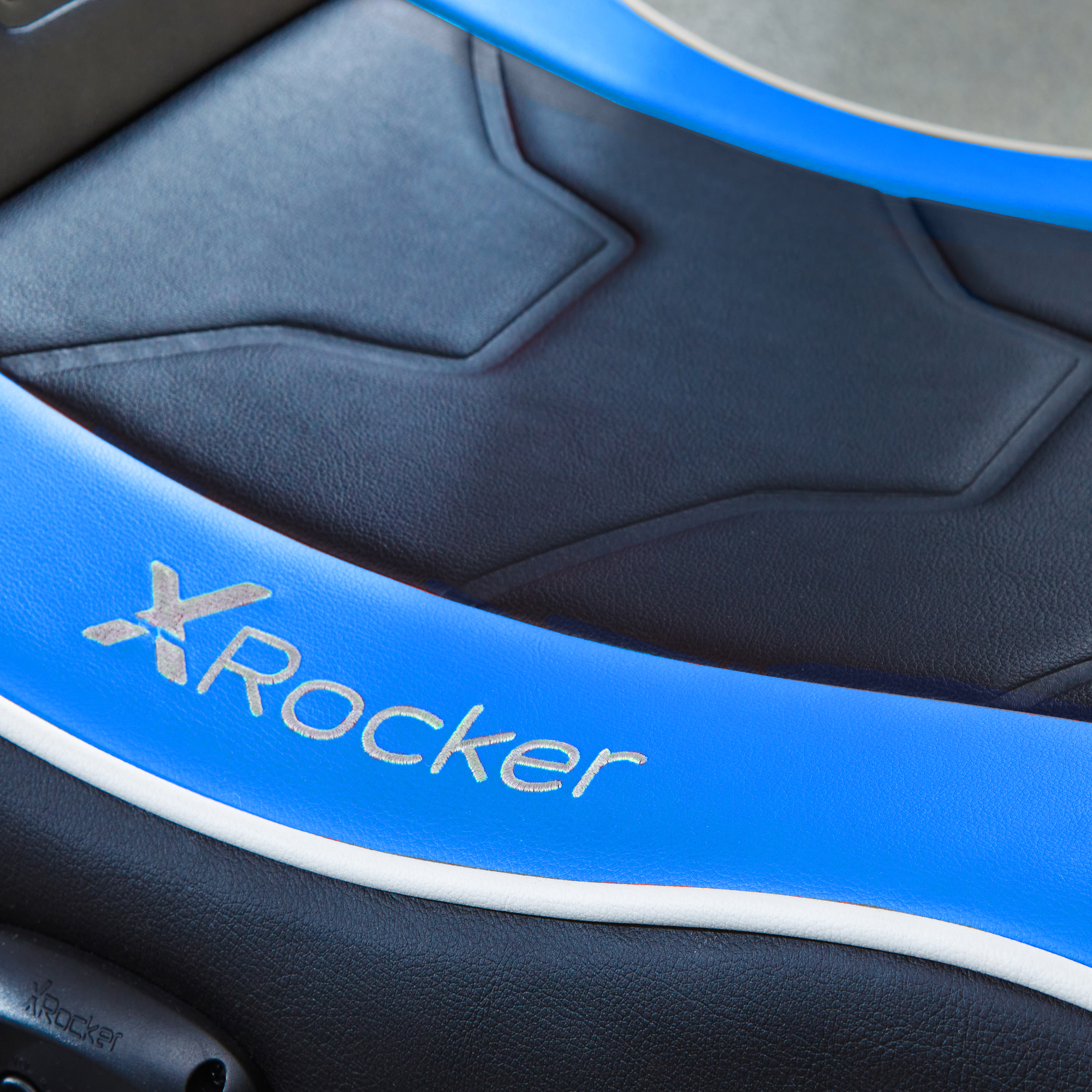 Nahaufnahme des Sitzes eines Gaming-Stuhls mit blauen und schwarzen Akzenten und dem Logo "X Rocker".