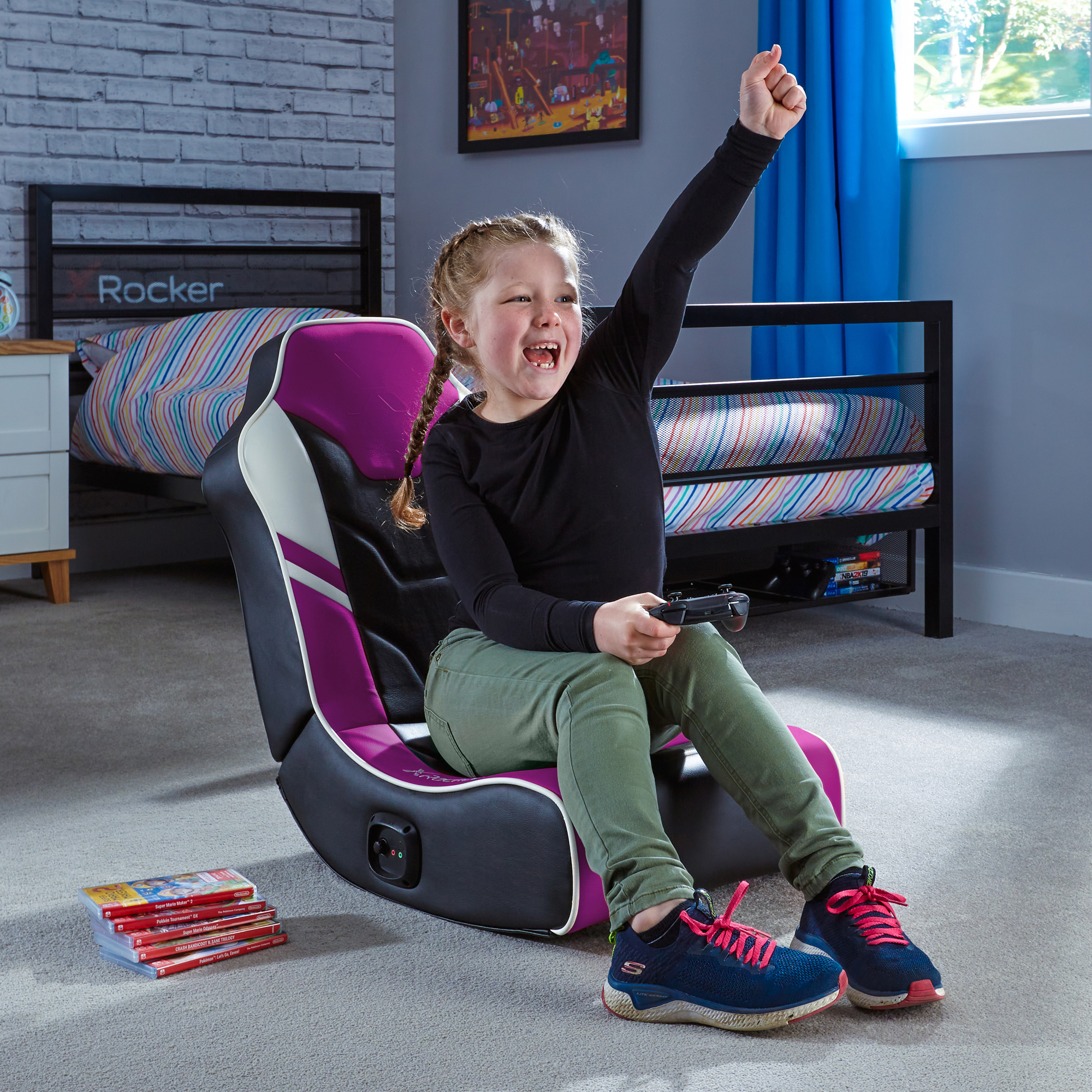 Junges Mädchen sitzt in einem Gaming-Stuhl, hält einen Controller und feiert.