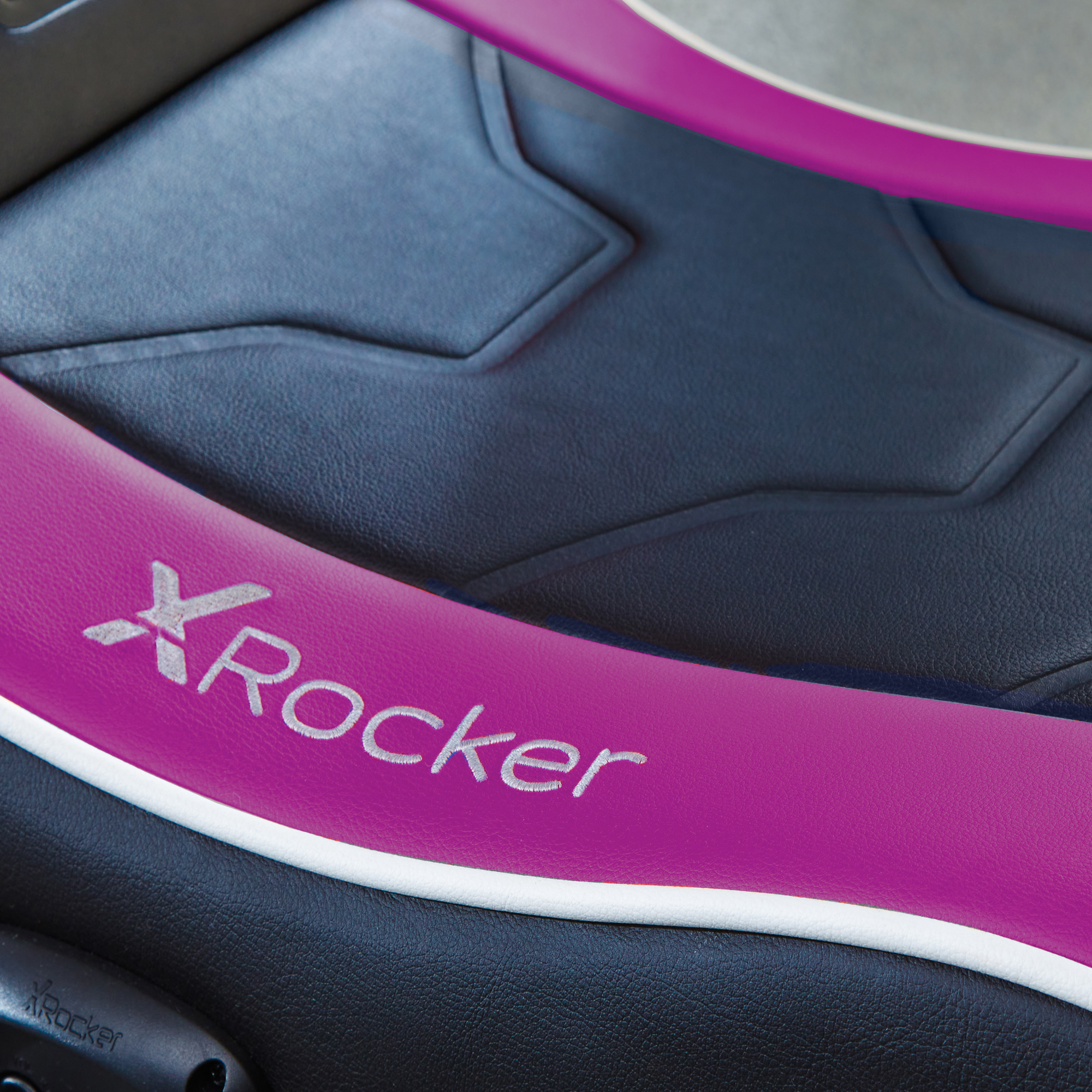 Nahaufnahme eines Gaming-Stuhls mit rosa Akzenten und dem Logo "XRockers" auf dem Sitz.