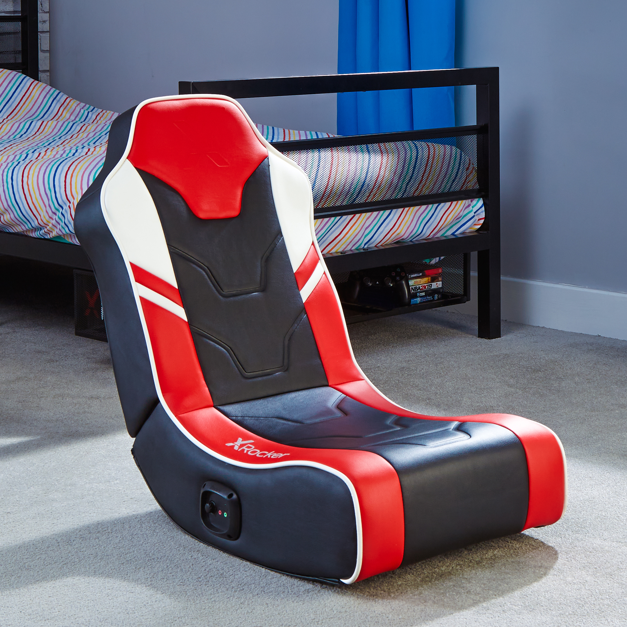 Gaming-Stuhl in einem Schlafzimmer. Der Stuhl ist rot, schwarz und weiß. Ein Bett ist im Hintergrund.