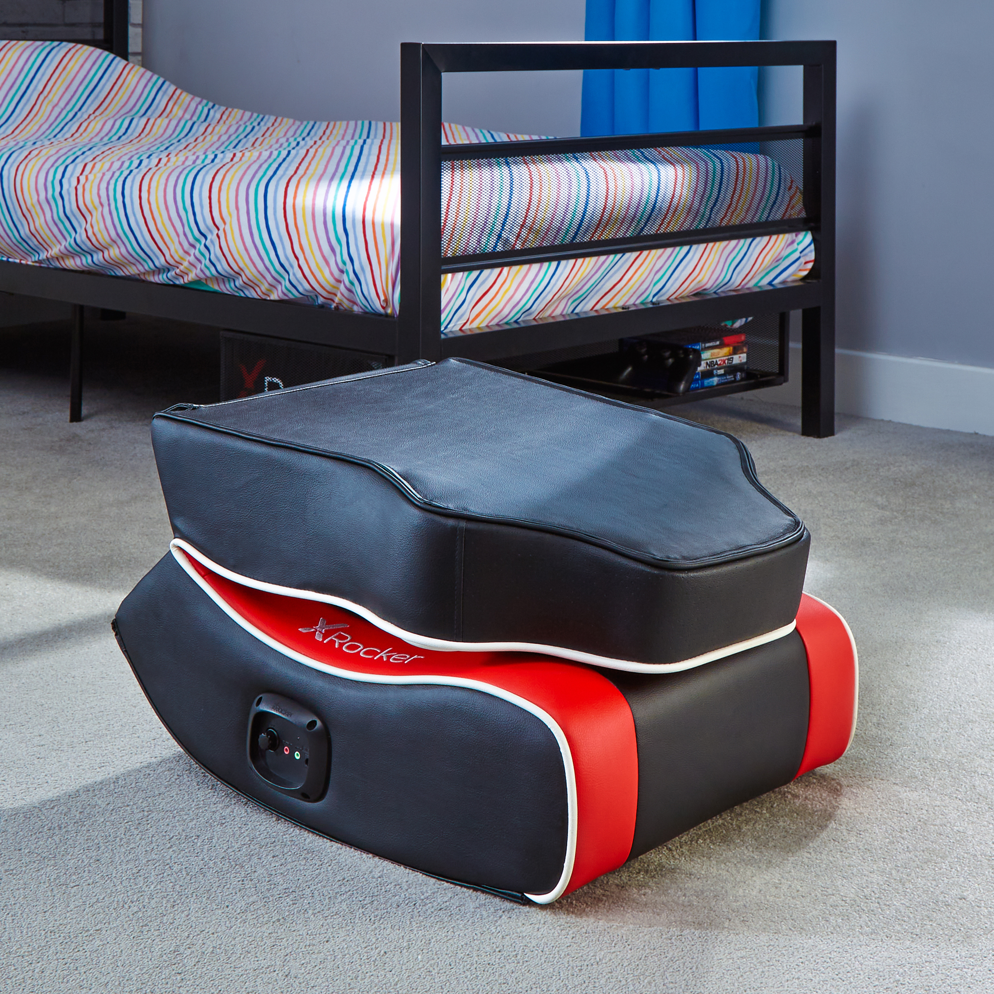 Gaming-Stuhl auf einem Teppich in einem Zimmer mit Bett. Schwarzer Stuhl mit roten Akzenten.