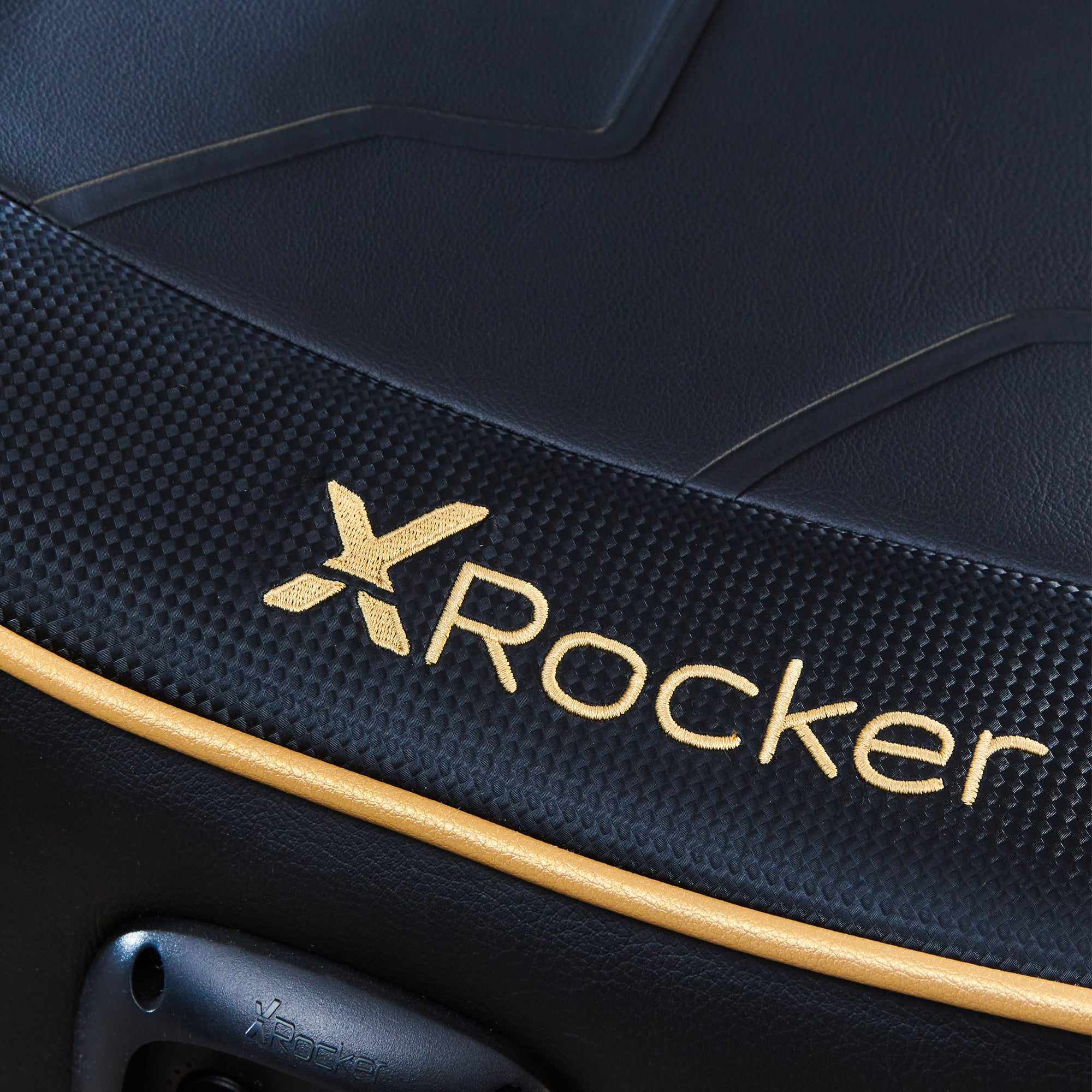 Nahaufnahme des Sitzes eines schwarzen Gaming-Stuhls. Das 'X Rocker'-Logo ist goldfarben.