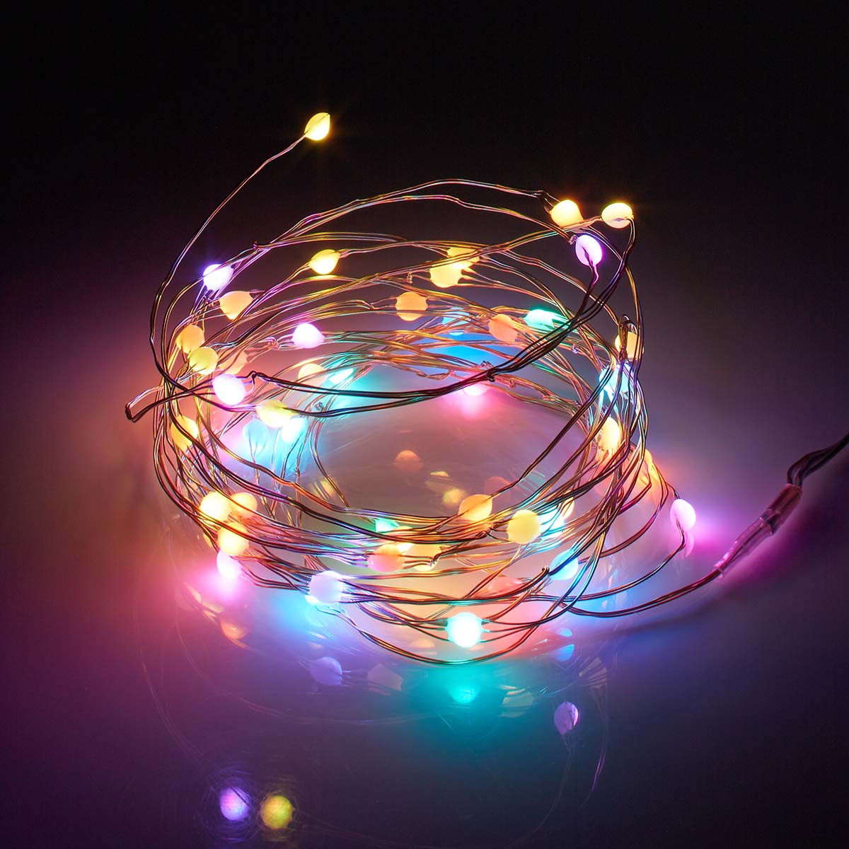Catena luminosa con LED multicolore, arrotolata su una superficie scura, con riflessi.