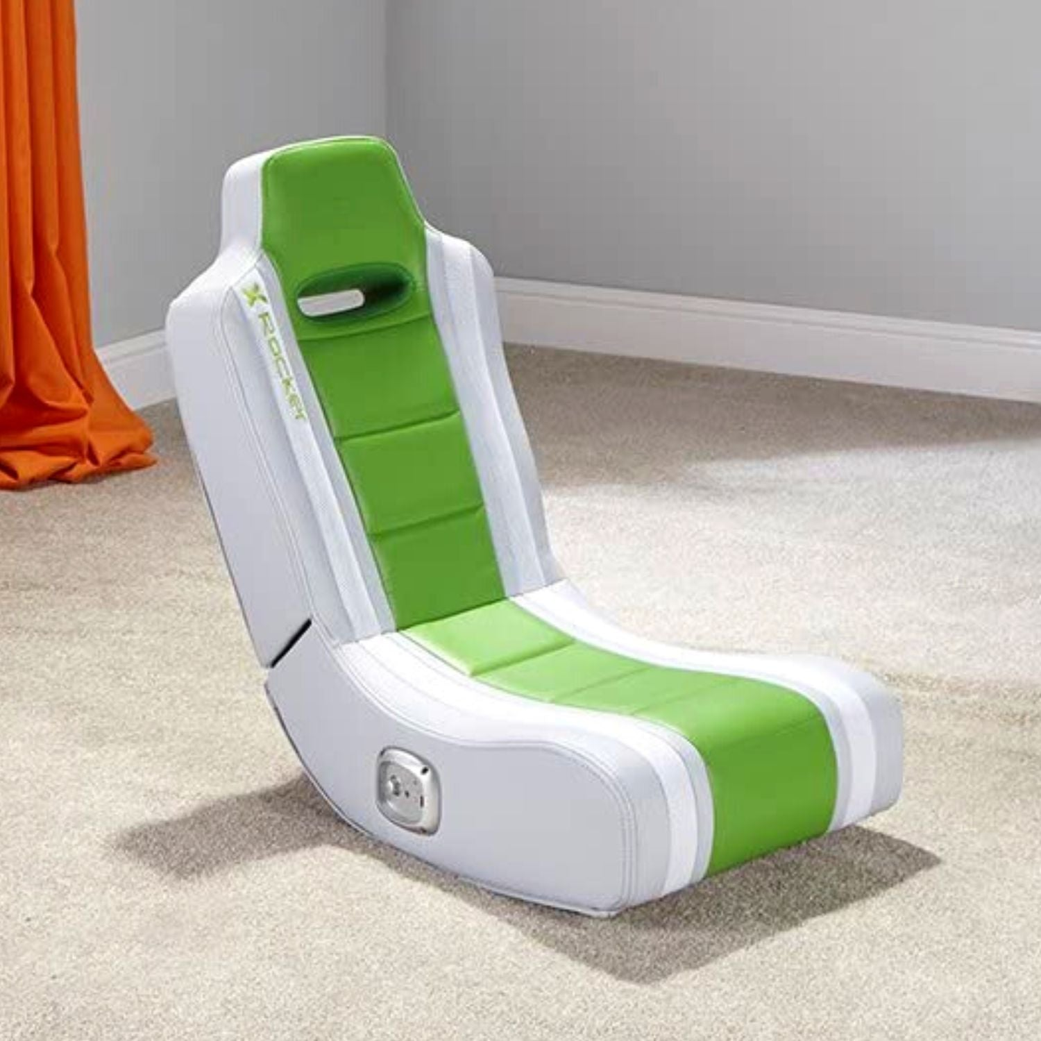 Grüner und weißer Gaming-Stuhl. Er steht auf einem beigen Teppich. Orange Vorhang im Hintergrund.