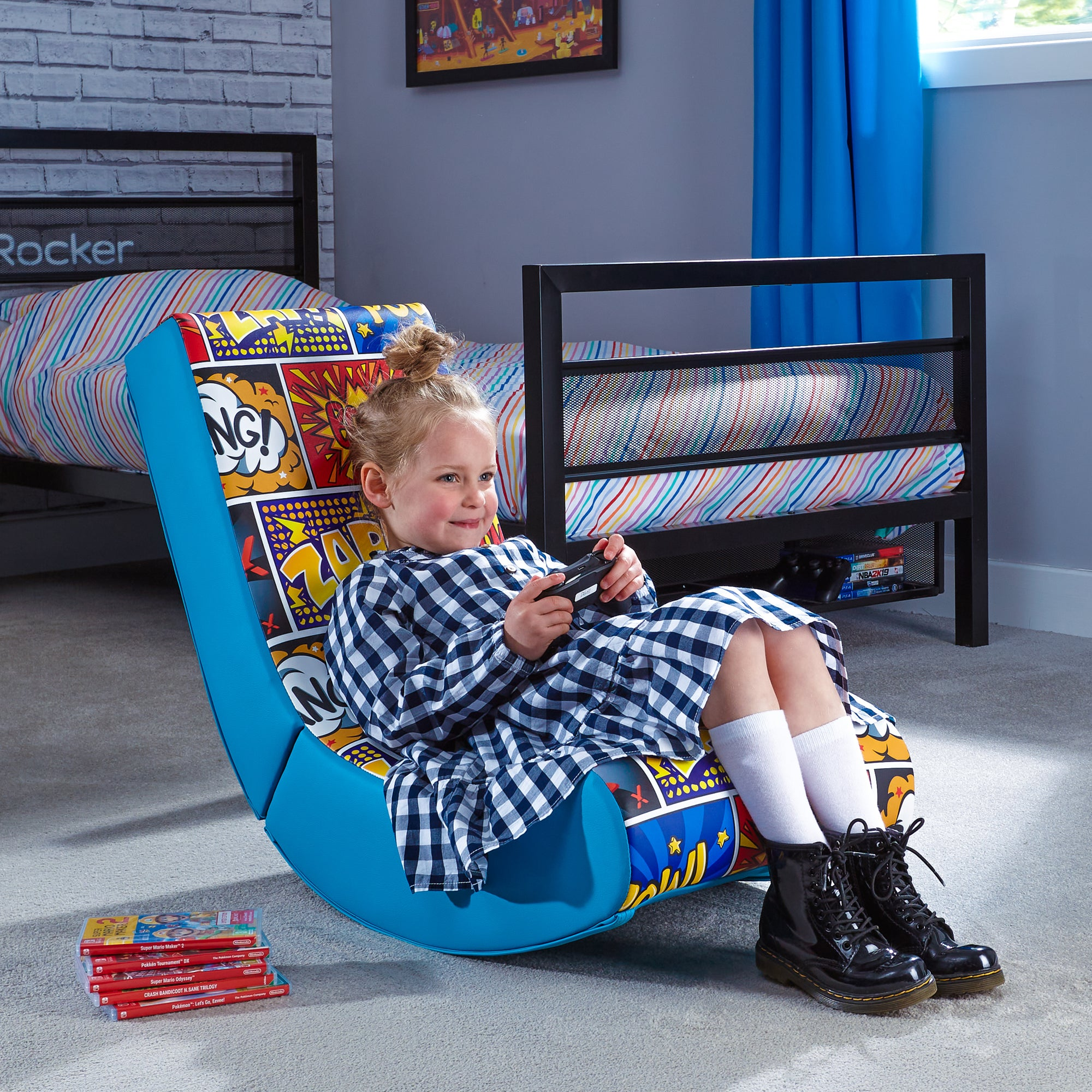 Ein Mädchen sitzt in einem blauen Schaukelstuhl und spielt mit einem Controller.