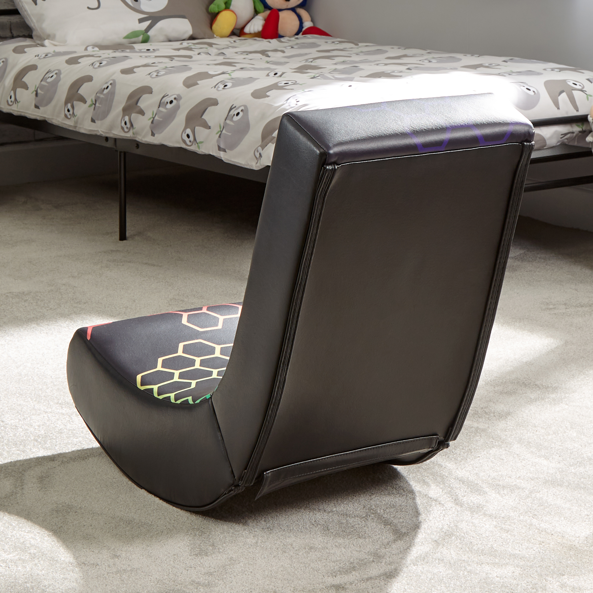 Ein schwarzer Gaming-Stuhl auf hellem Teppich. Der Stuhl hat ein farbenfrohes Design auf dem Sitz.