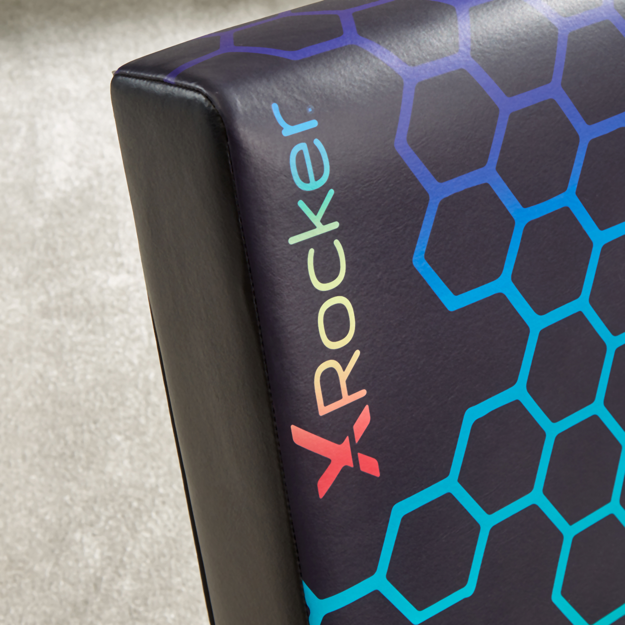 Schwarze Stuhlecke mit farbenfrohem XRockeR-Logo und sechseckigem Muster.