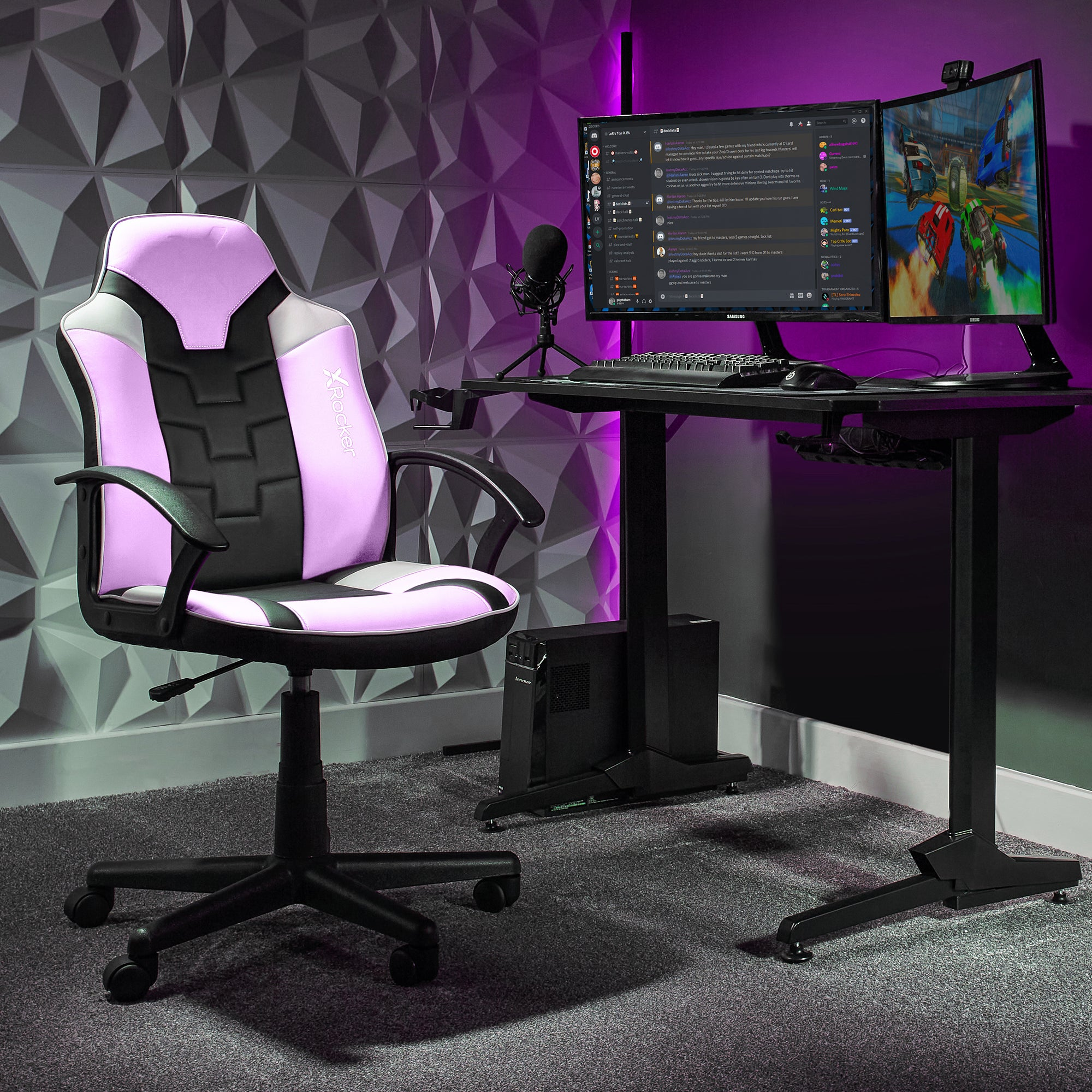 Gaming-Setup: rosa-schwarzer Stuhl, Dual-Monitore mit Spiel und Chat, Schreibtisch, Mikrofon und PC-Tower.