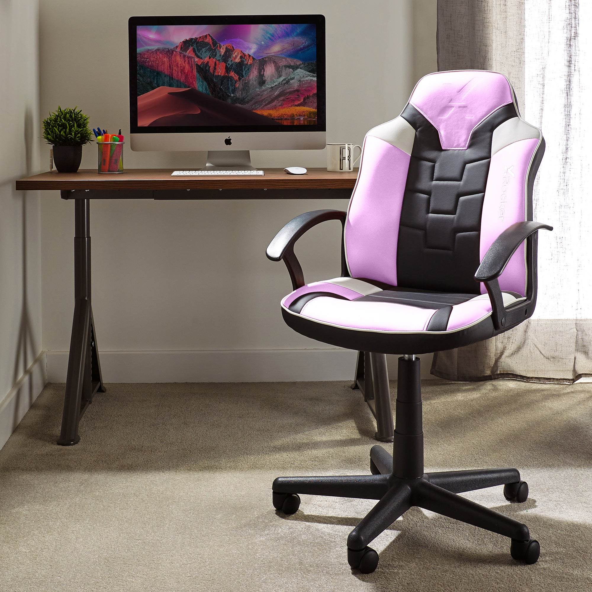 Ein pinkfarbener und schwarzer Gaming-Stuhl in einem Raum mit Schreibtisch und Computer.