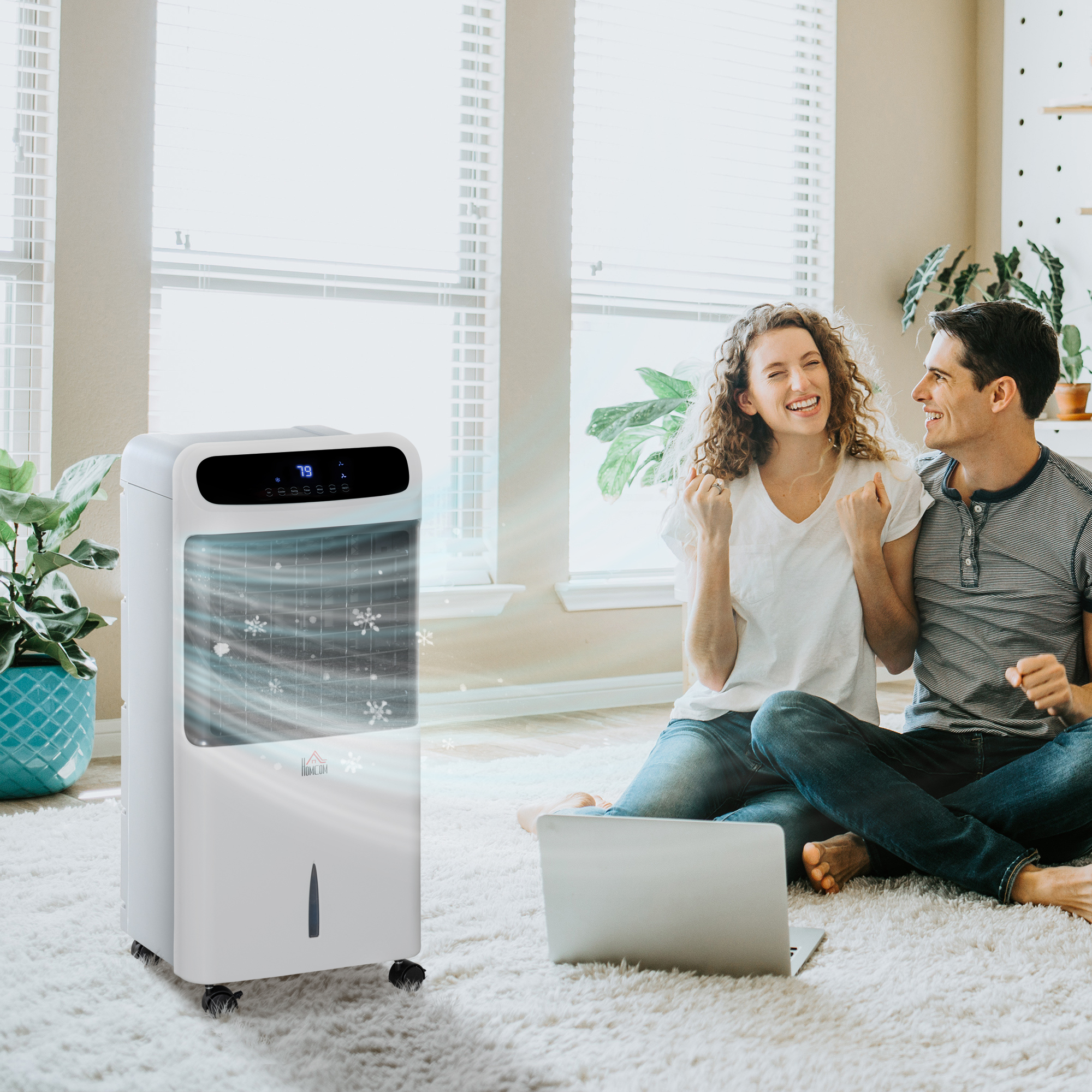 Una pareja está sentada en una sala de estar. Un enfriador de aire blanco está funcionando, y una computadora portátil está en el suelo.
