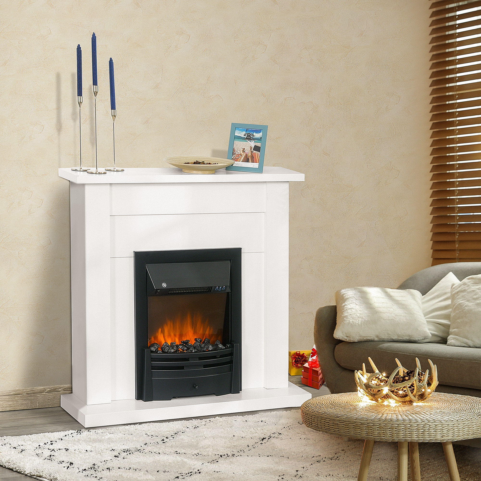 Chimenea blanca con interior negro, llama decorativa y estante con velas y marco de fotos.