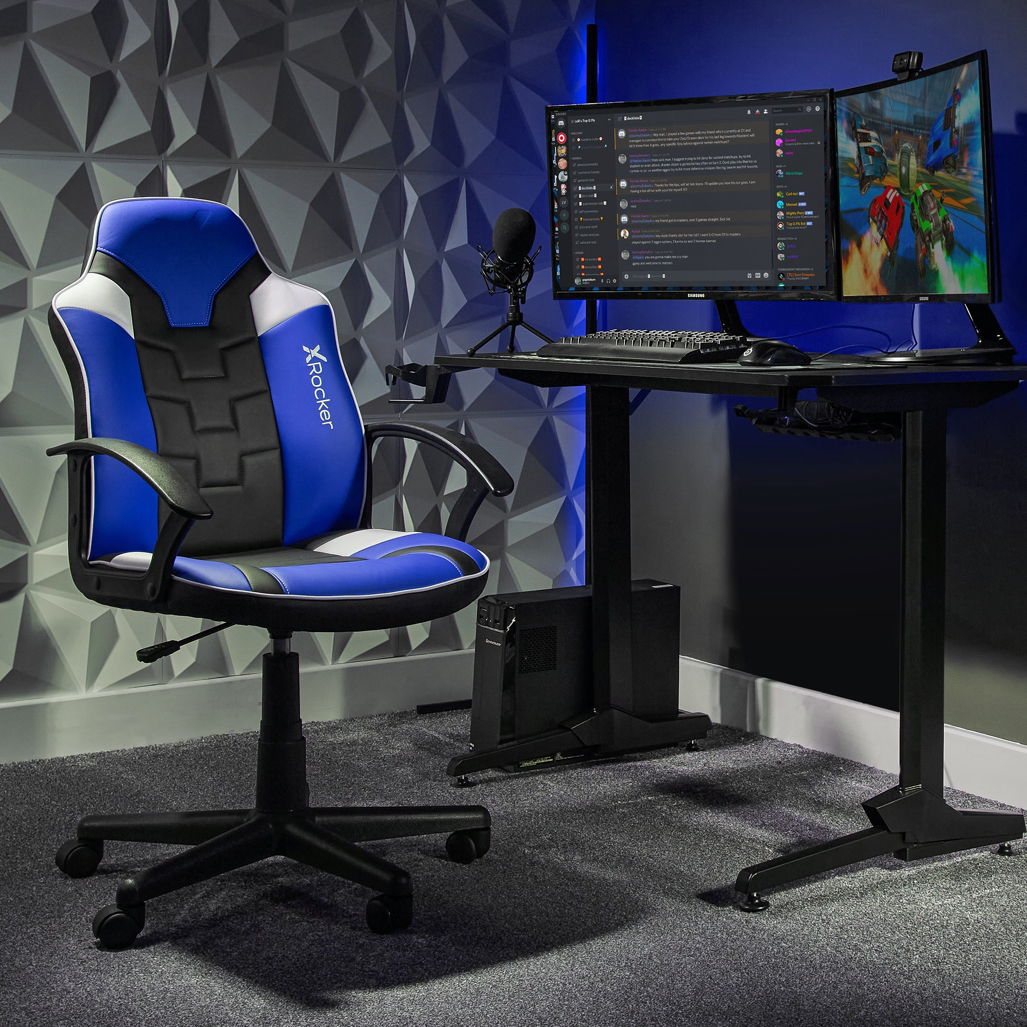 Gaming-Setup mit blau-schwarzem Stuhl, zwei Monitoren, Schreibtisch, Mikrofon und PC-Tower.